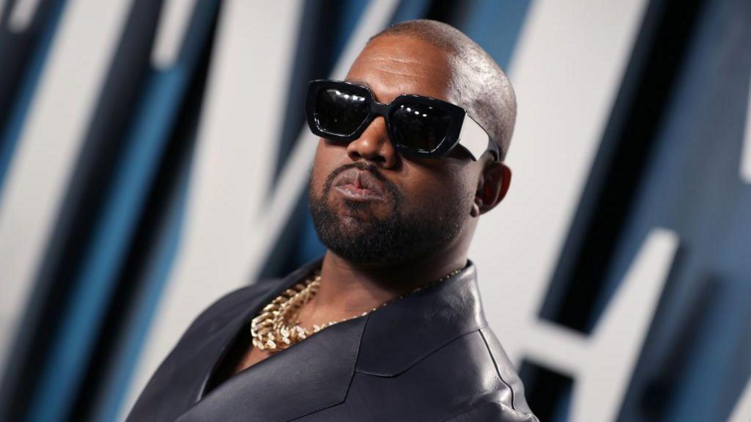 Kanye West performing live on stage under intense concert lighting