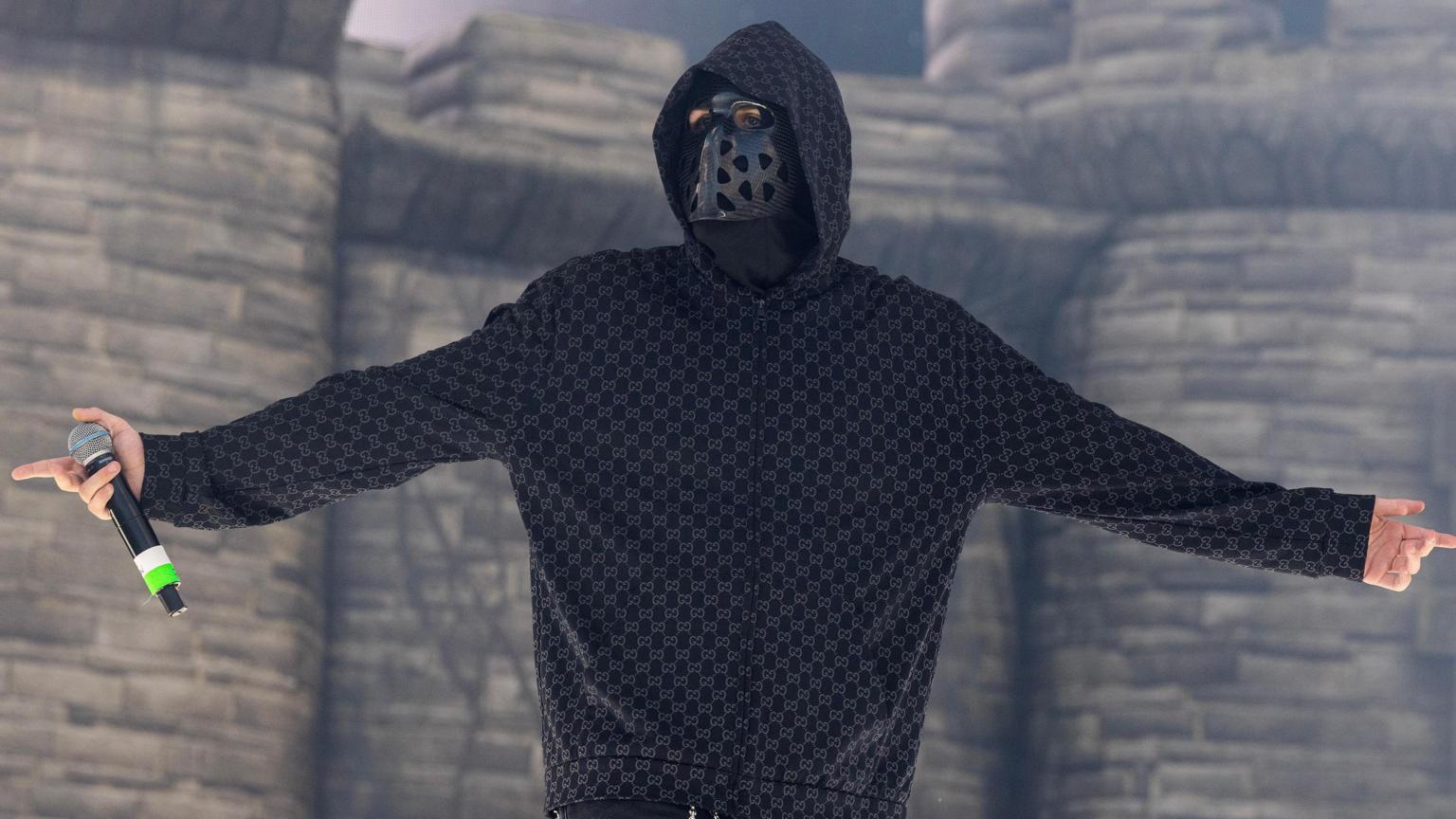 An anonymous masked rapper performing on stage at a music festival.