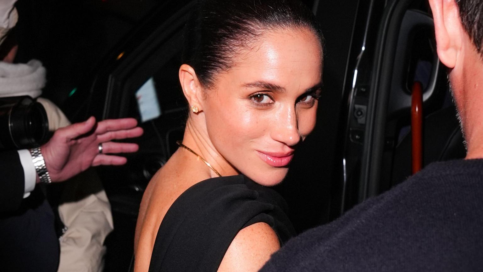 Meghan Markle smiling at an event in a chic outfit