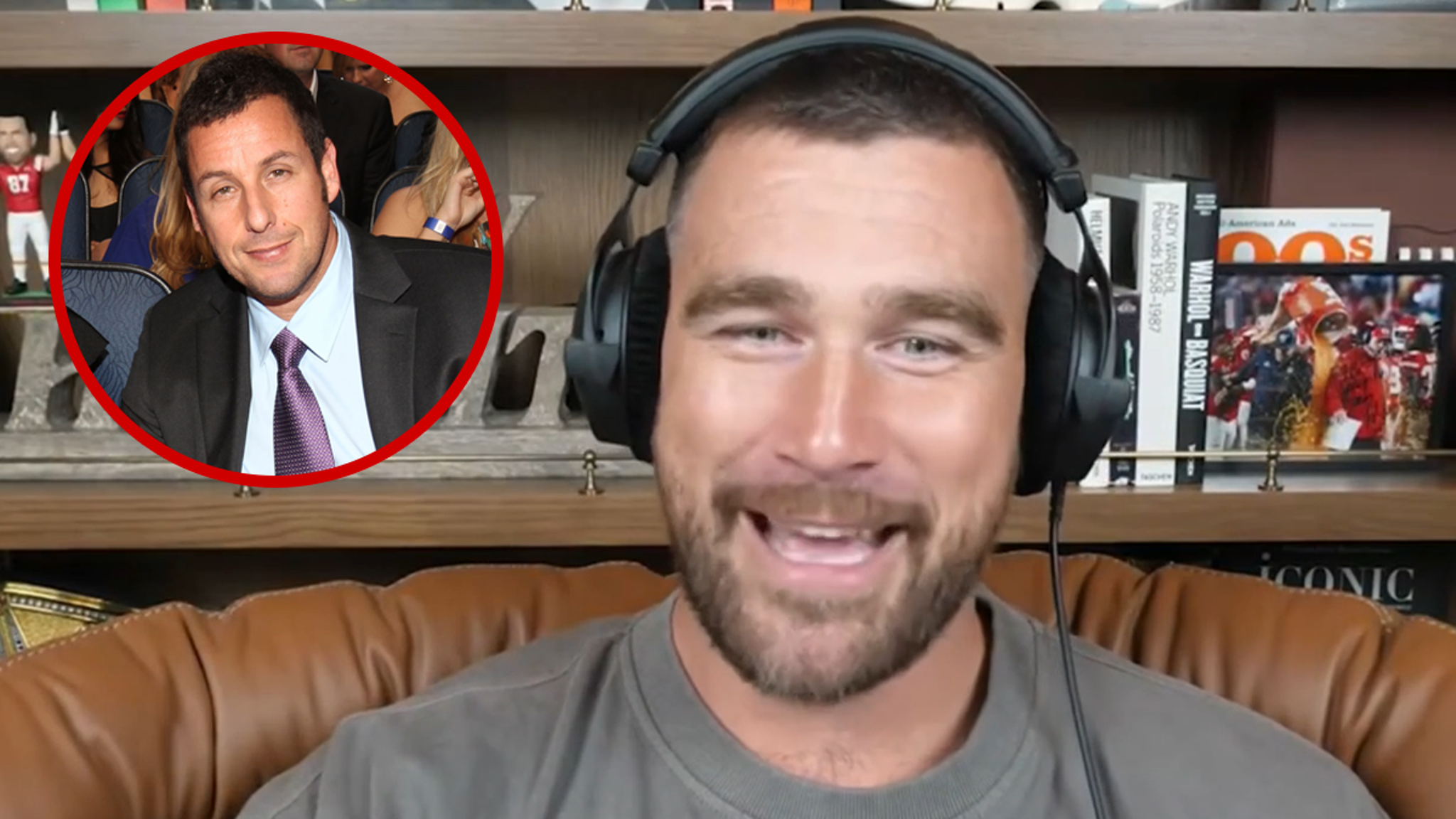 Travis Kelce smiling at an event while Adam Sandler speaks