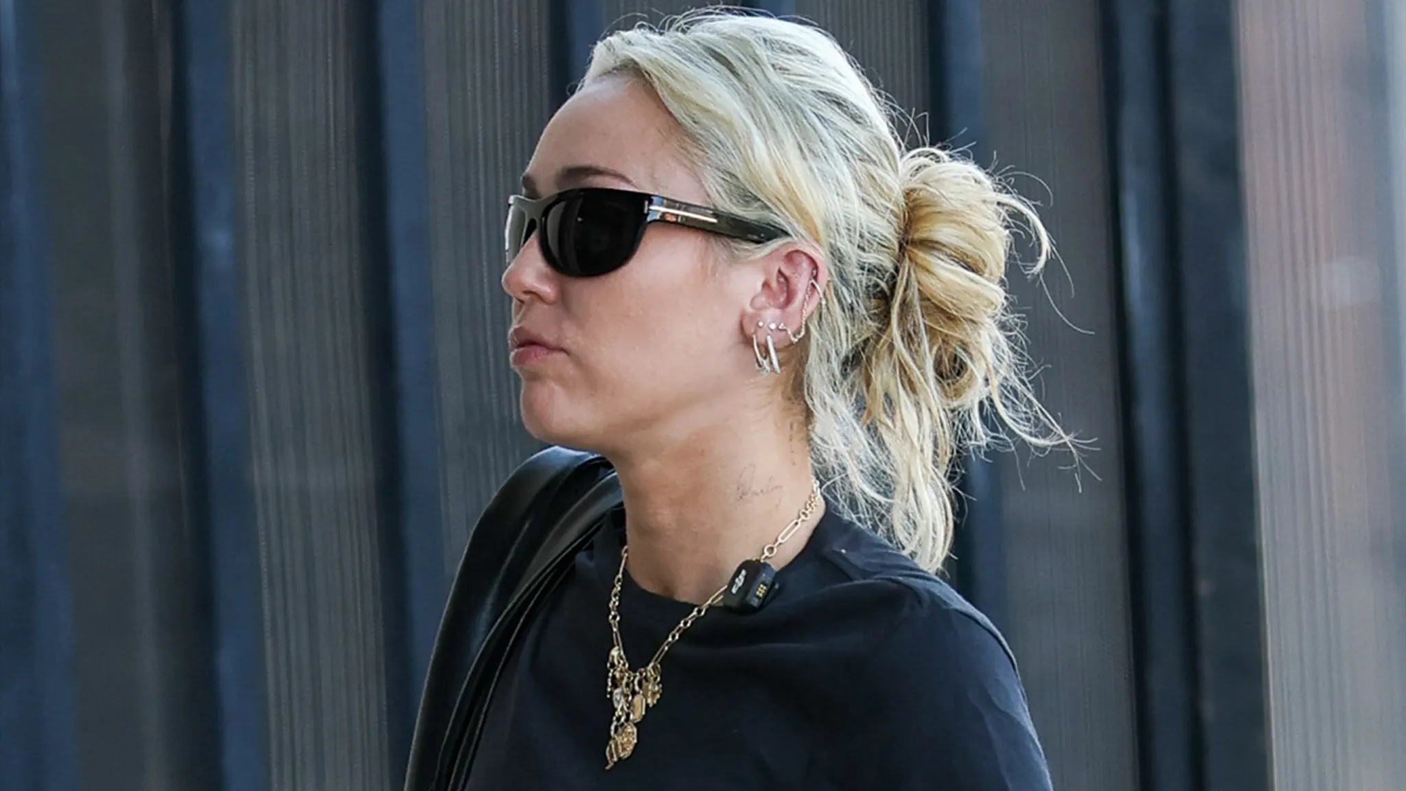 Miley Cyrus wearing sunglasses and an all-black outfit outside a Los Angeles studio