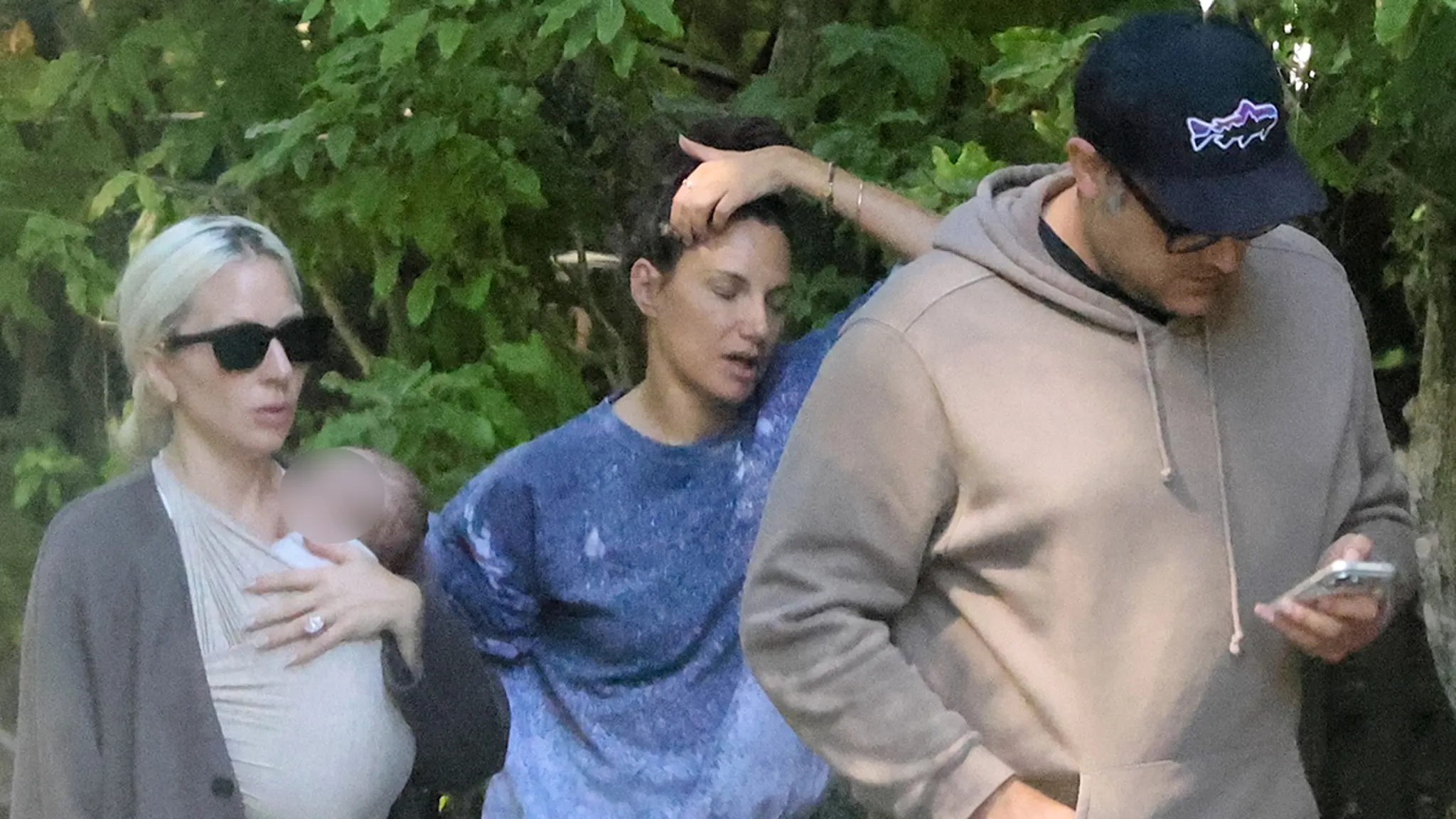 Lady Gaga holding her swaddled newborn baby close to her chest alongside fiancé Michael Polansky