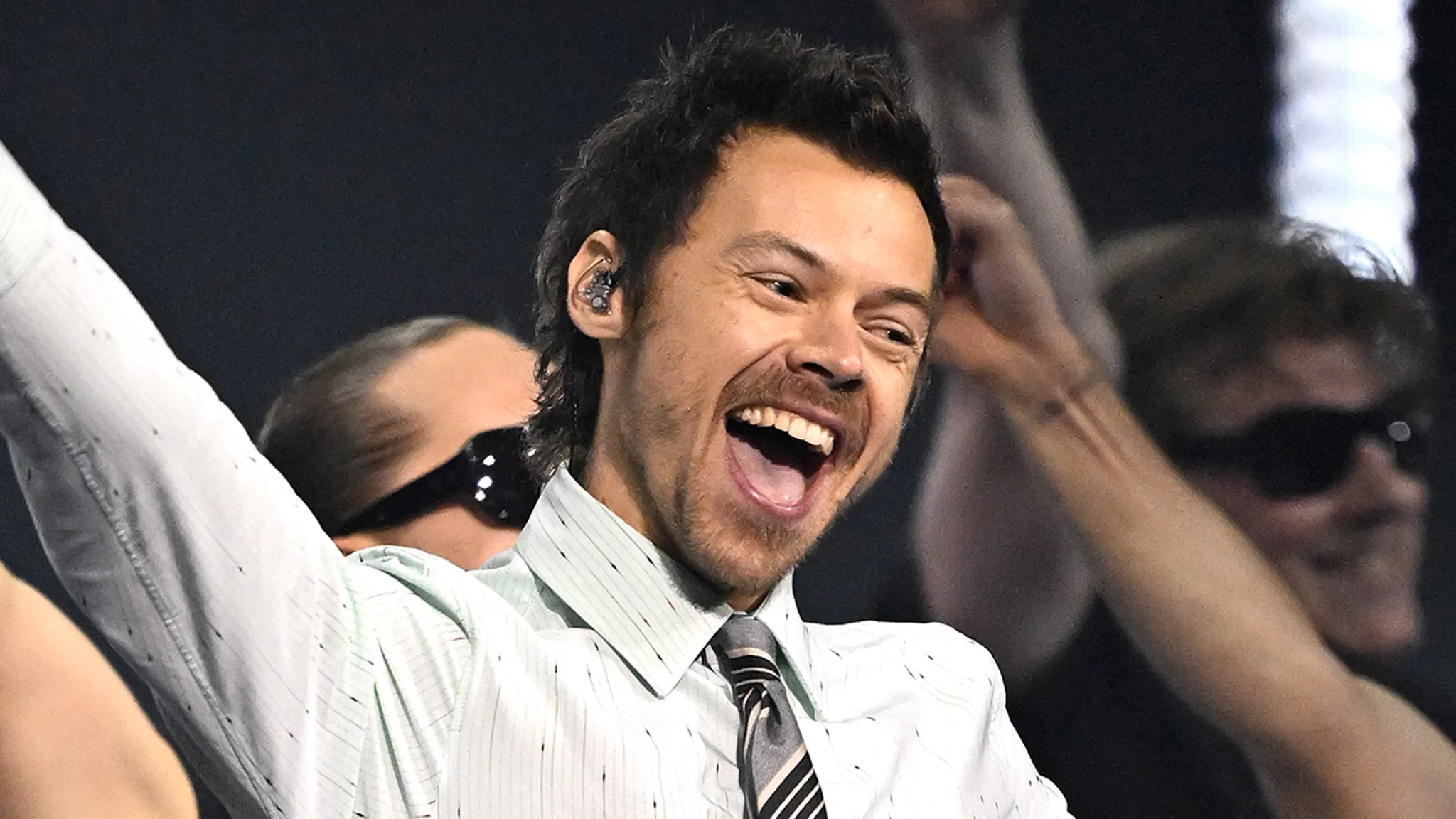 Harry Styles performing on stage in front of a live stadium audience