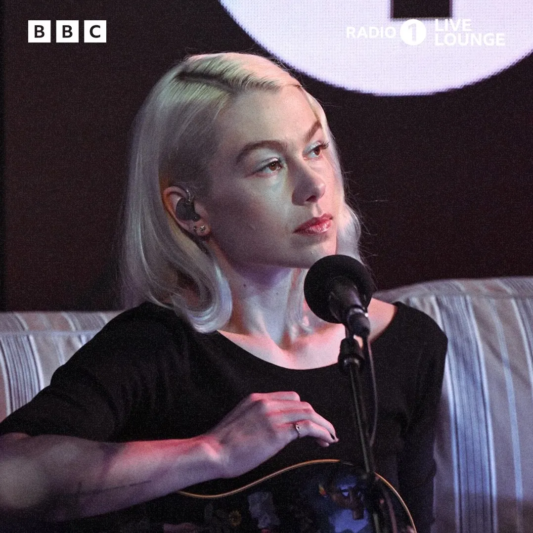Phoebe Bridgers performing live with a guitar on stage