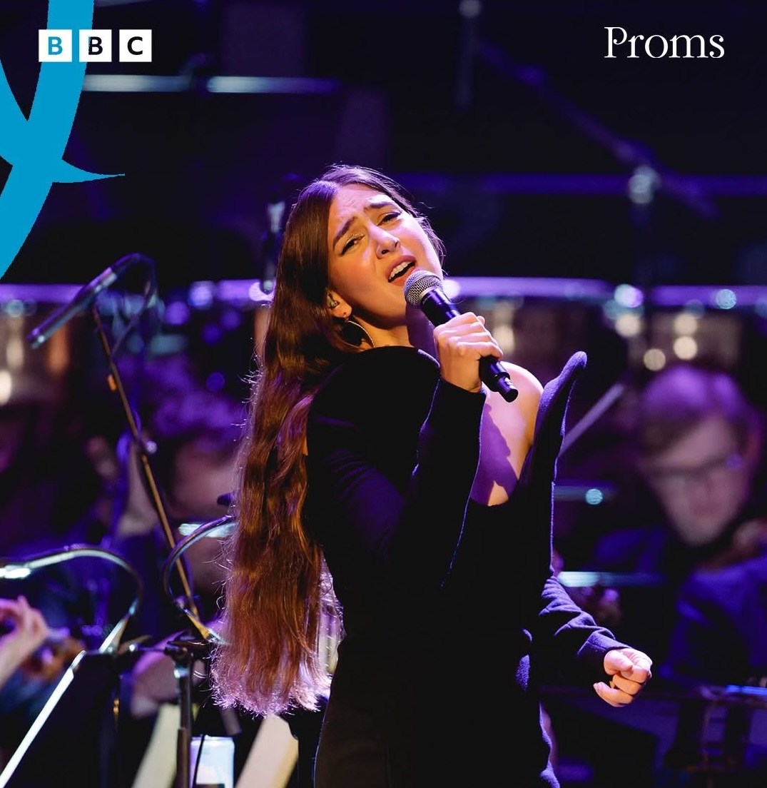 Weyes Blood performing live on stage with an orchestra