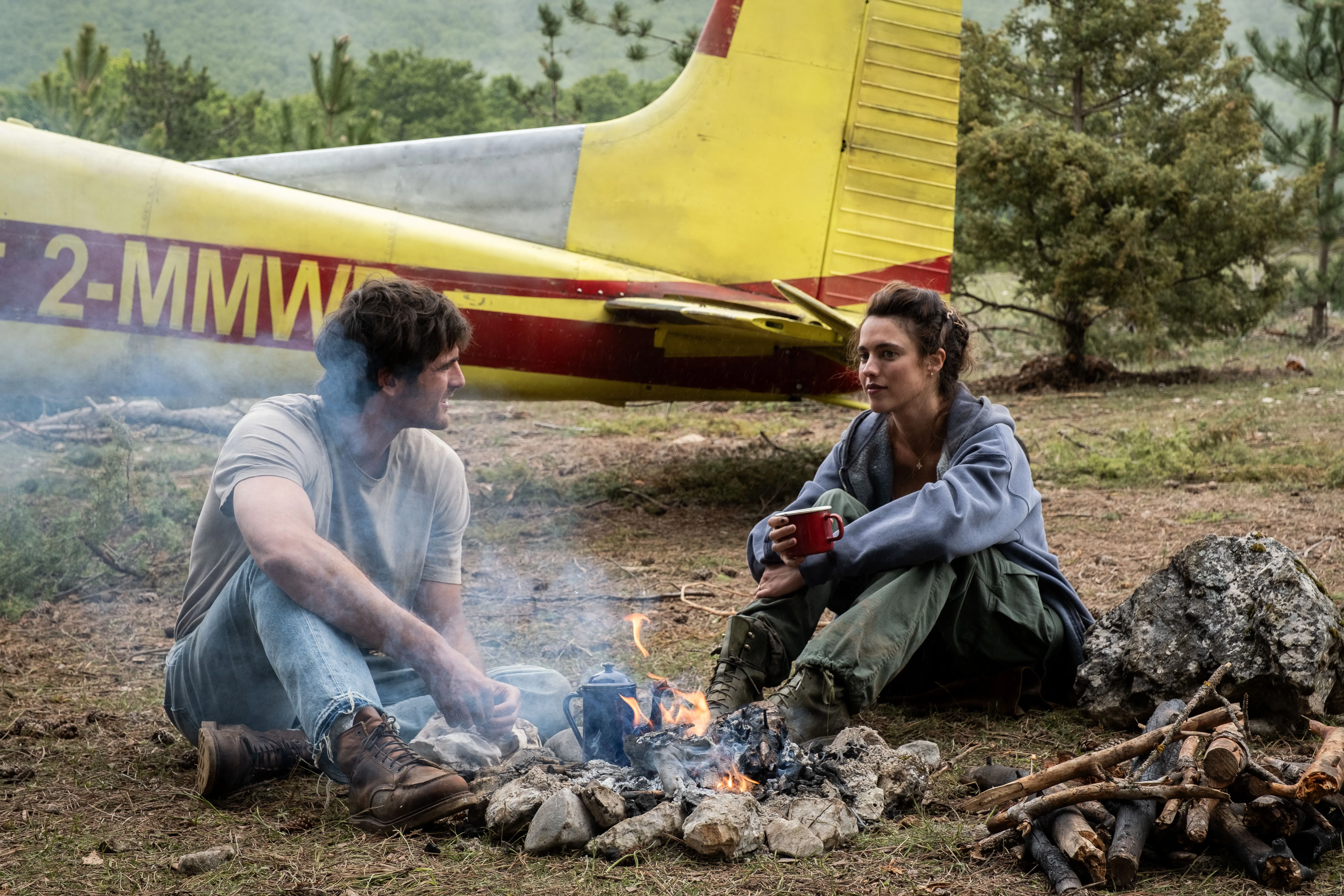 Jacob Elordi and Margaret Qualley sitting by a campfire in a scene from "The Dog Stars."