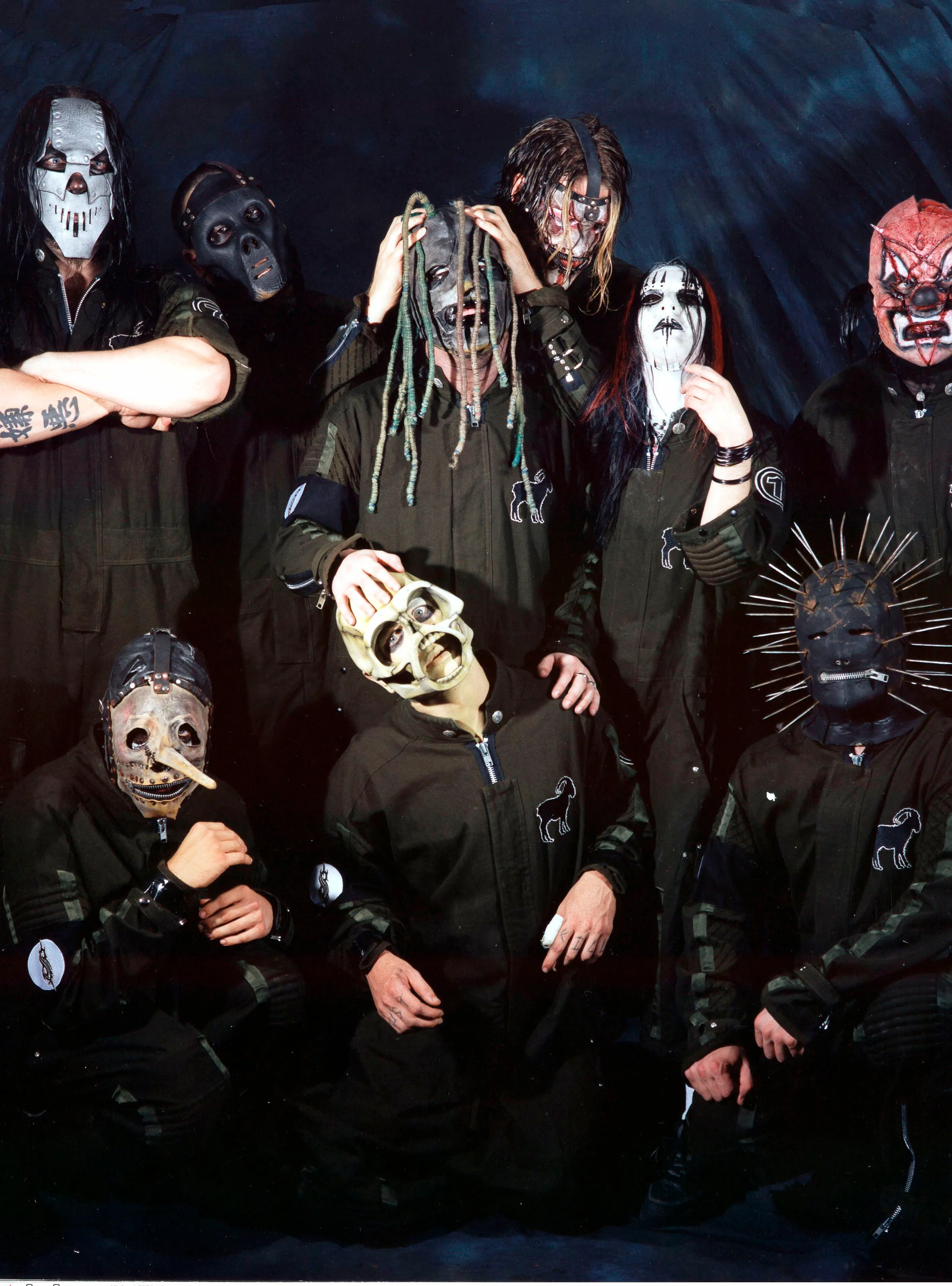 Slipknot band members in masks and jumpsuits pose for a group photo.