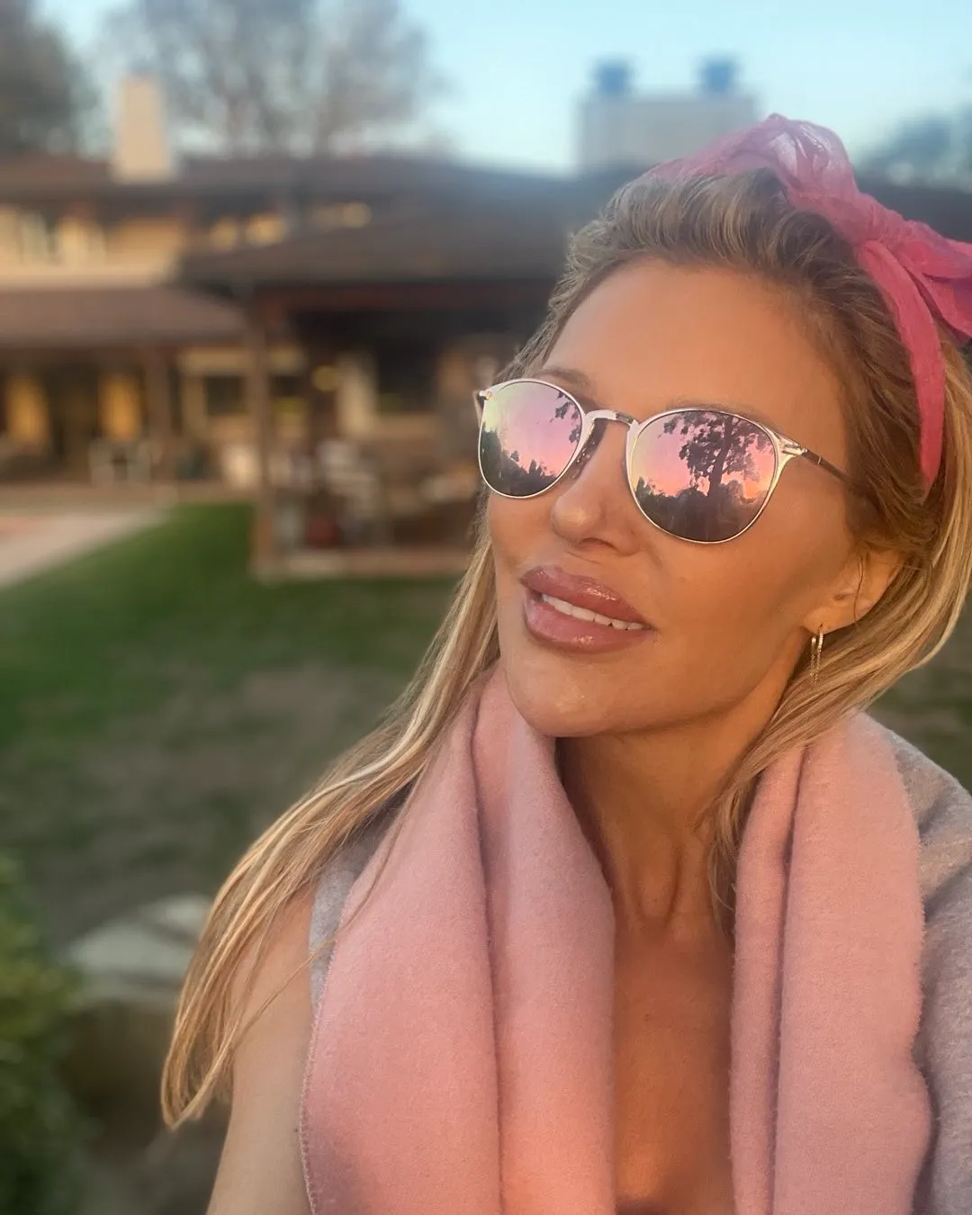 Brandi Glanville wearing mirrored sunglasses and a pink scarf.