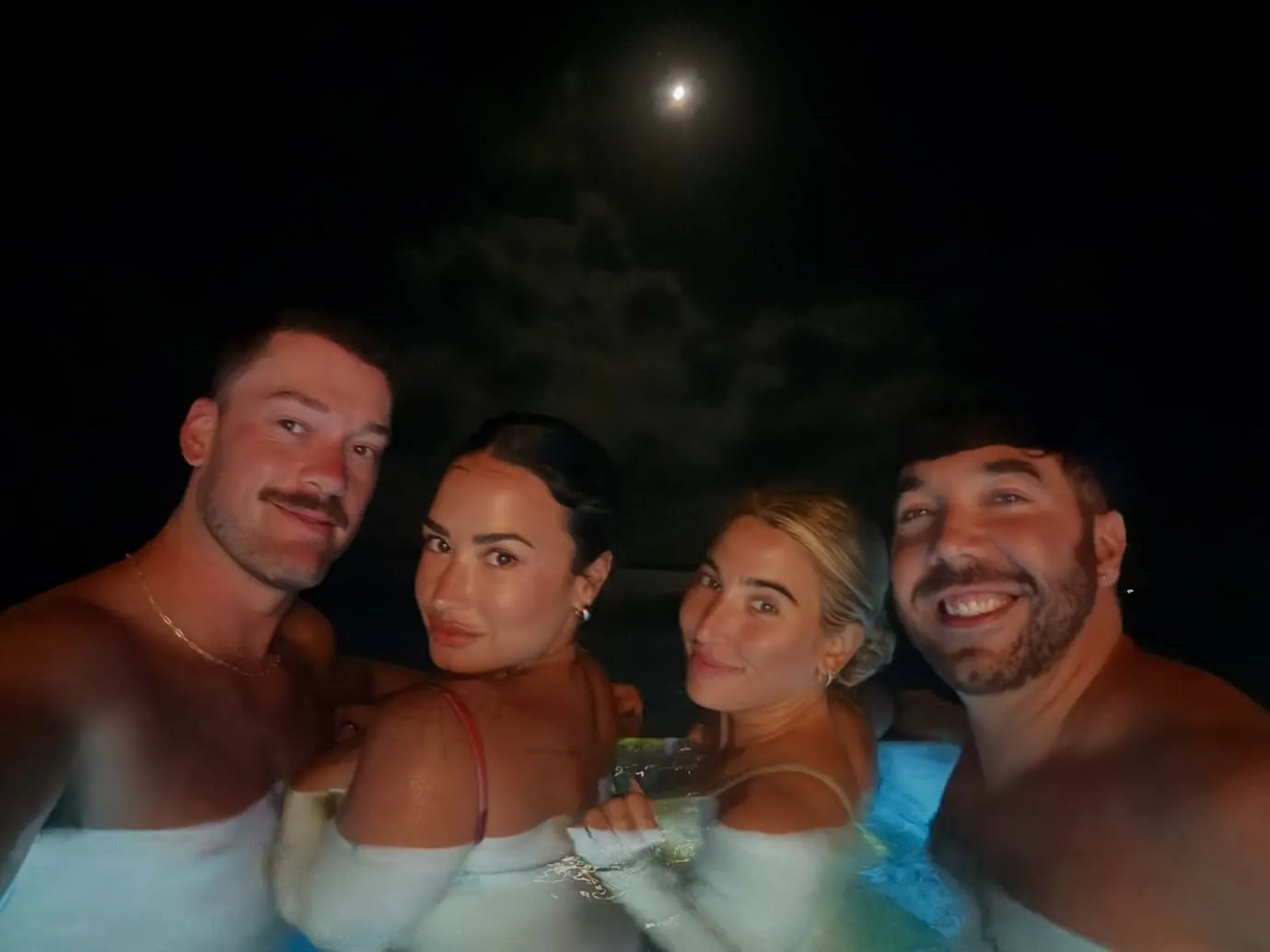 Demi Lovato and friends in a hot tub at night.