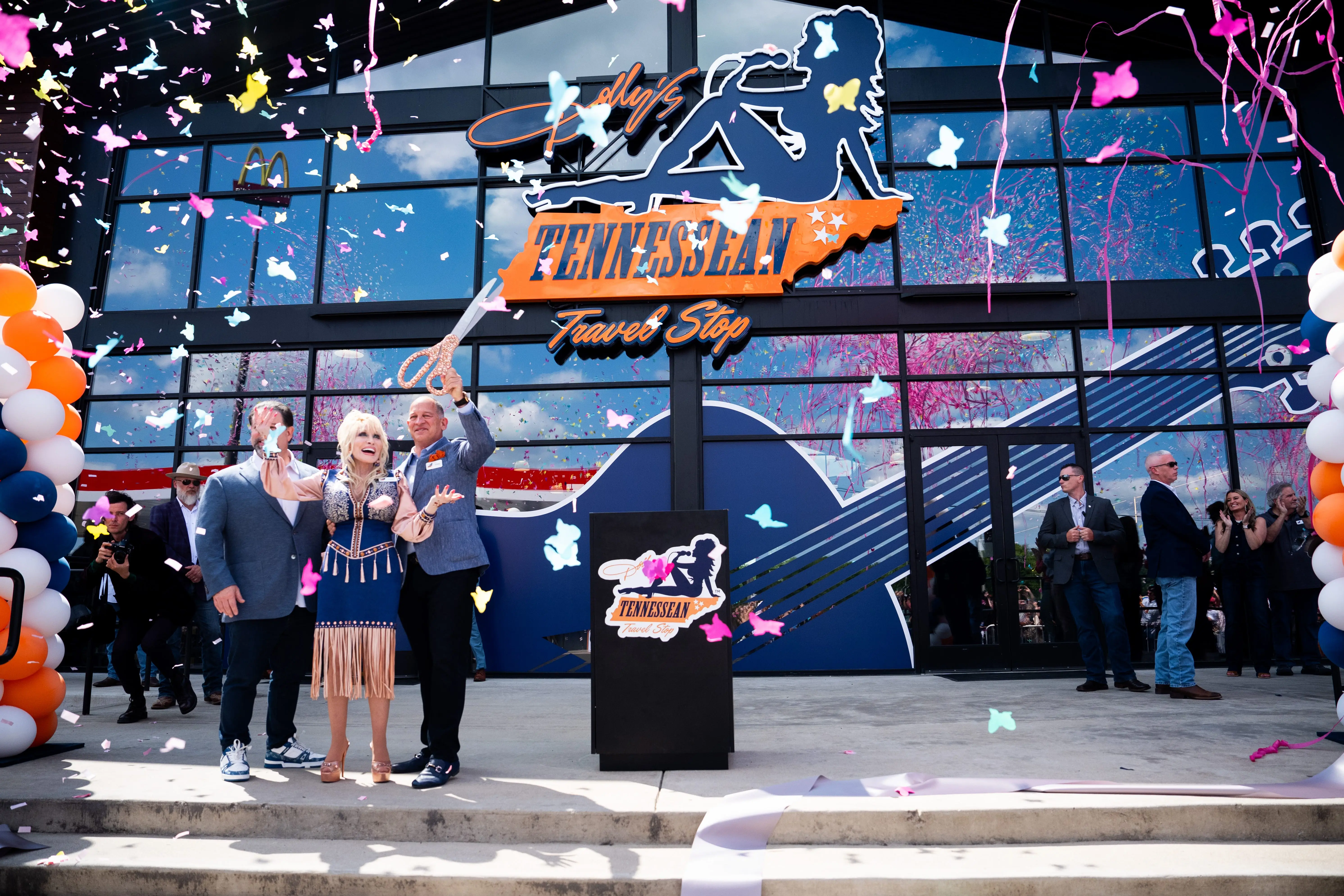 Dolly Parton and Greg Sachs wave to a crowd after cutting a ceremonial ribbon during the grand opening of Dolly