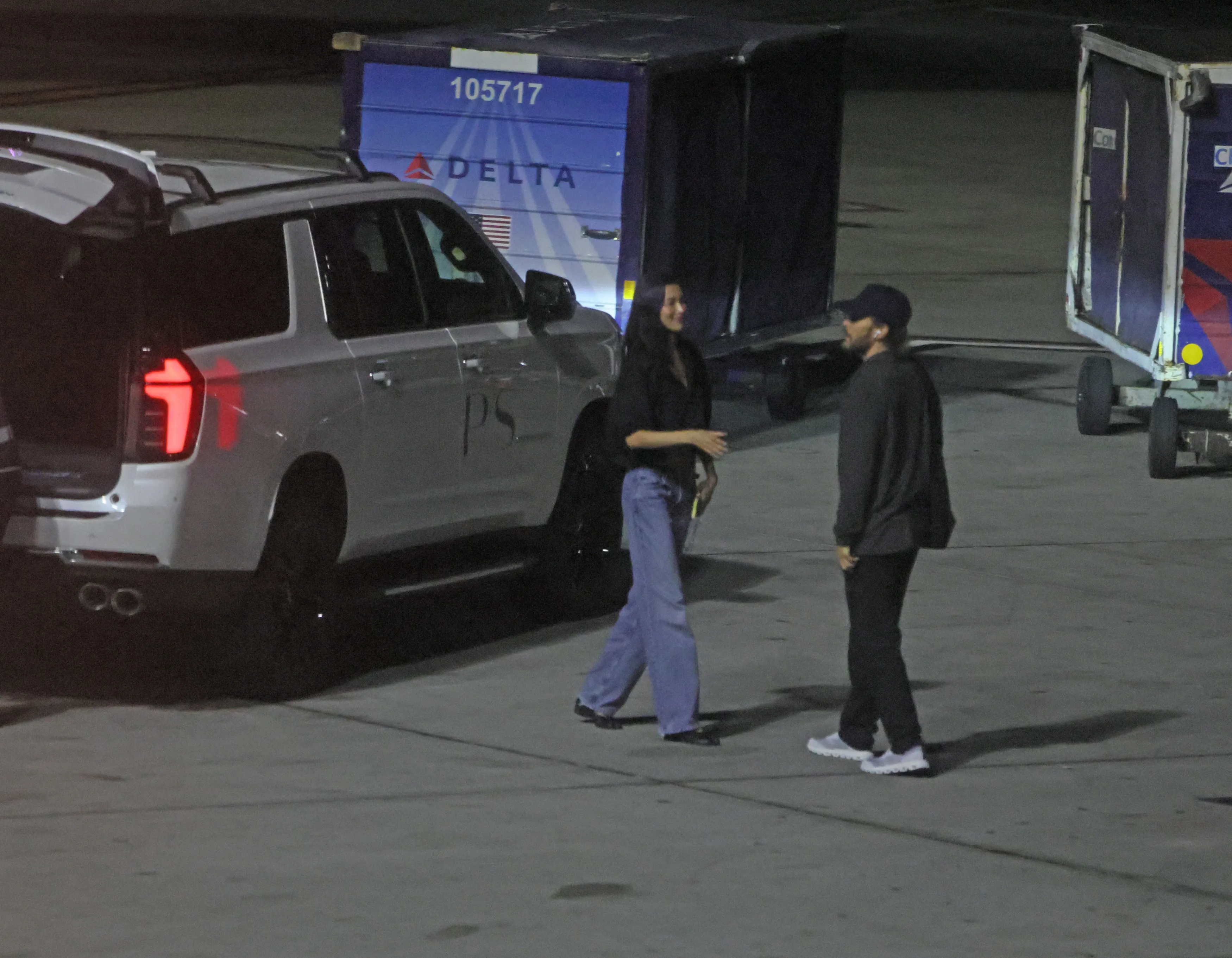 Jared Leto and Thet Thinn on the tarmac at LAX, with a Delta cargo container in the background.