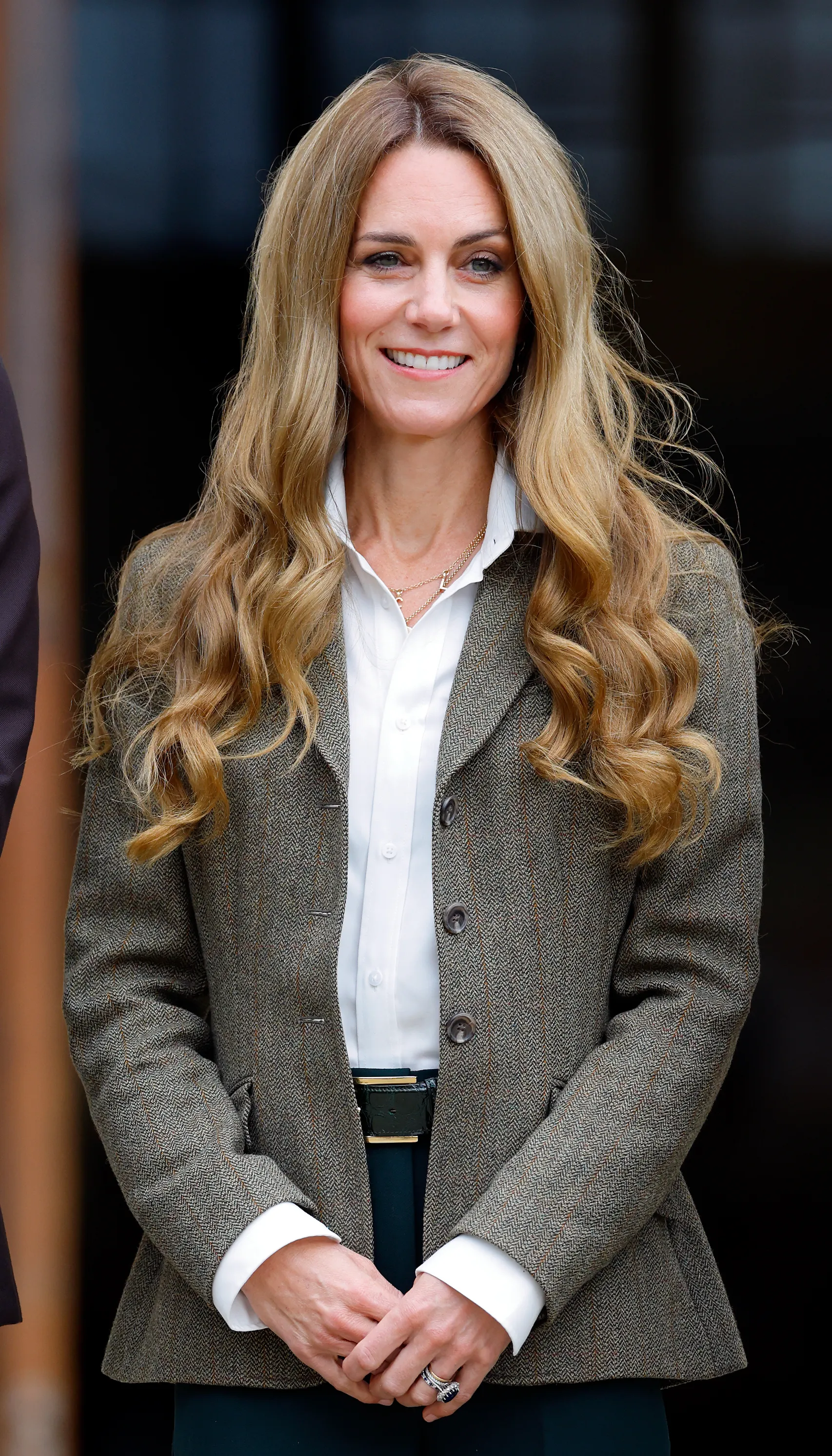 Catherine, Princess of Wales, smiles, wearing a white shirt and tweed jacket.