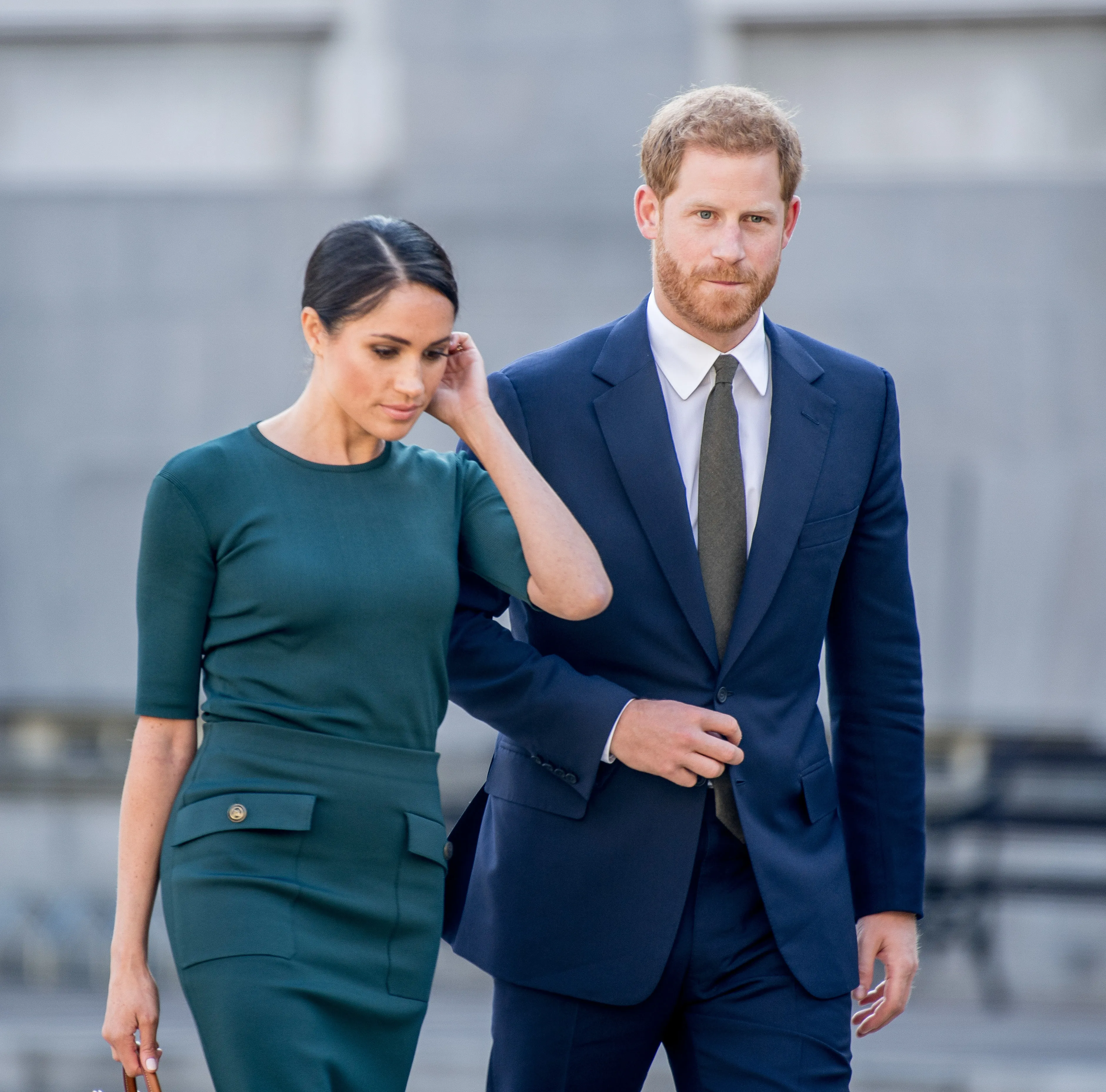 Meghan Markle, Duchess of Sussex, in a teal dress, holding Prince Harry
