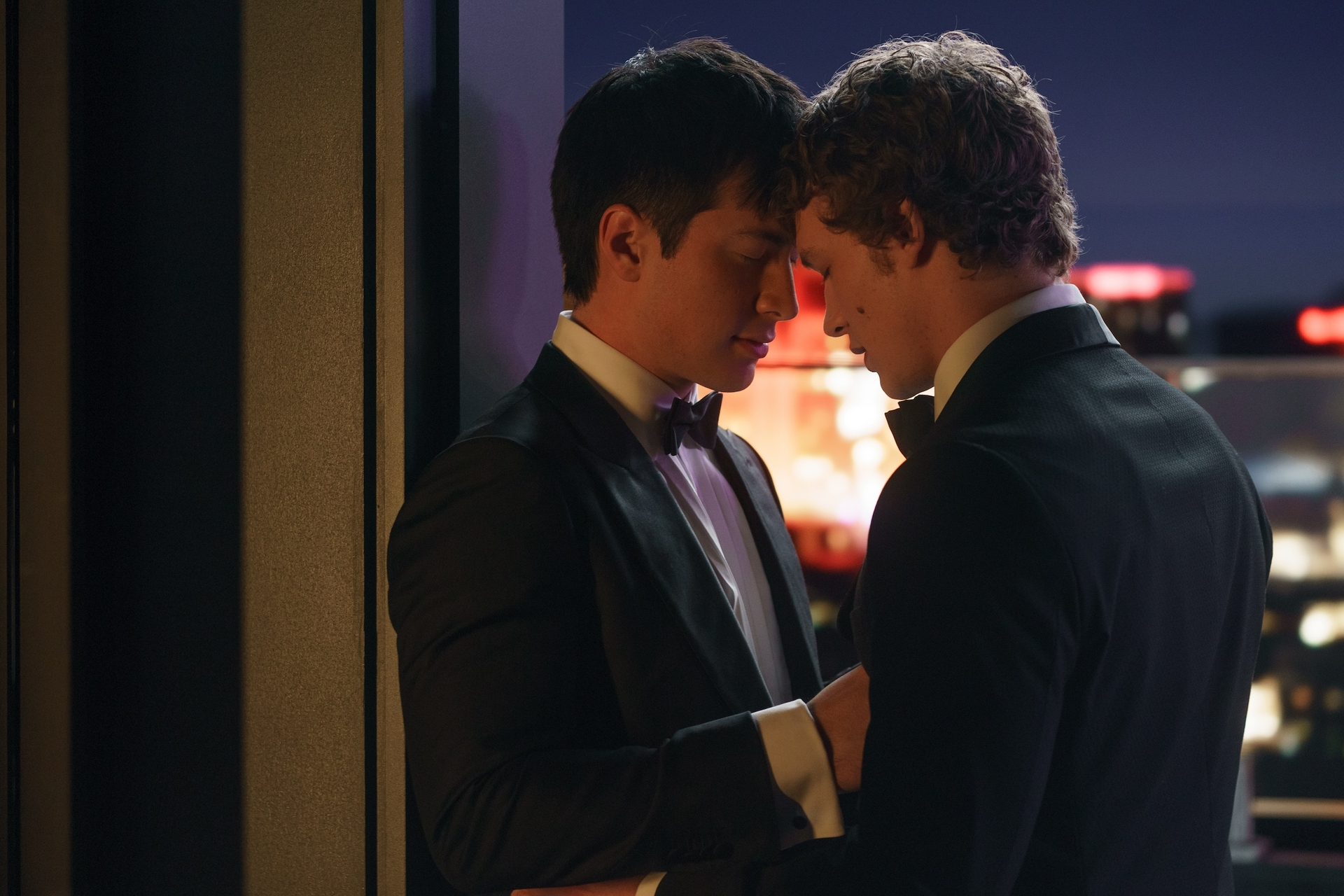 Hudson Williams and Connor Storrie in tuxedos, foreheads touching, in a scene from "Heated Rivalry."