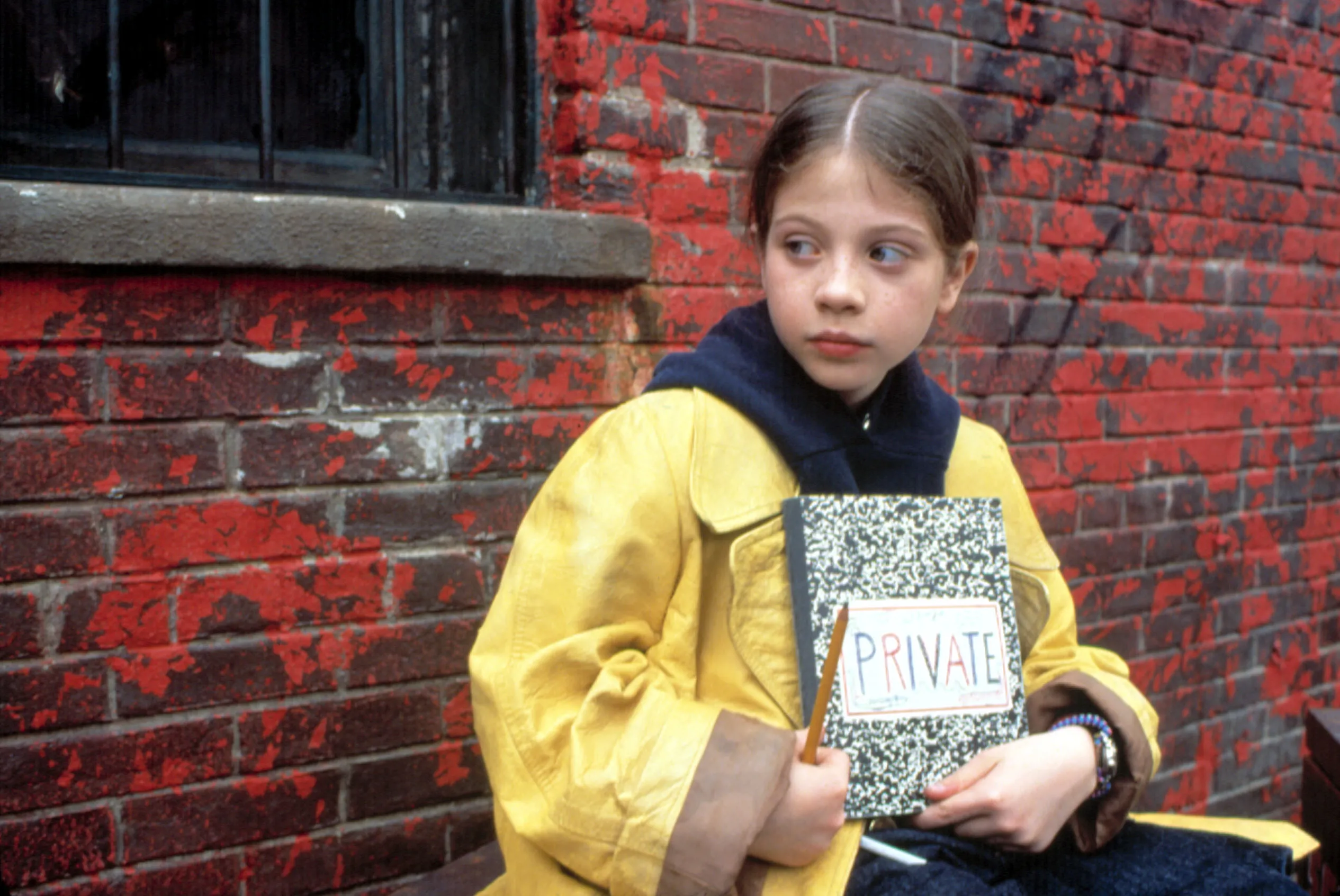 Michelle Trachtenberg as Harriet the Spy, wearing a yellow raincoat and holding a notebook with "PRIVATE" written on it.