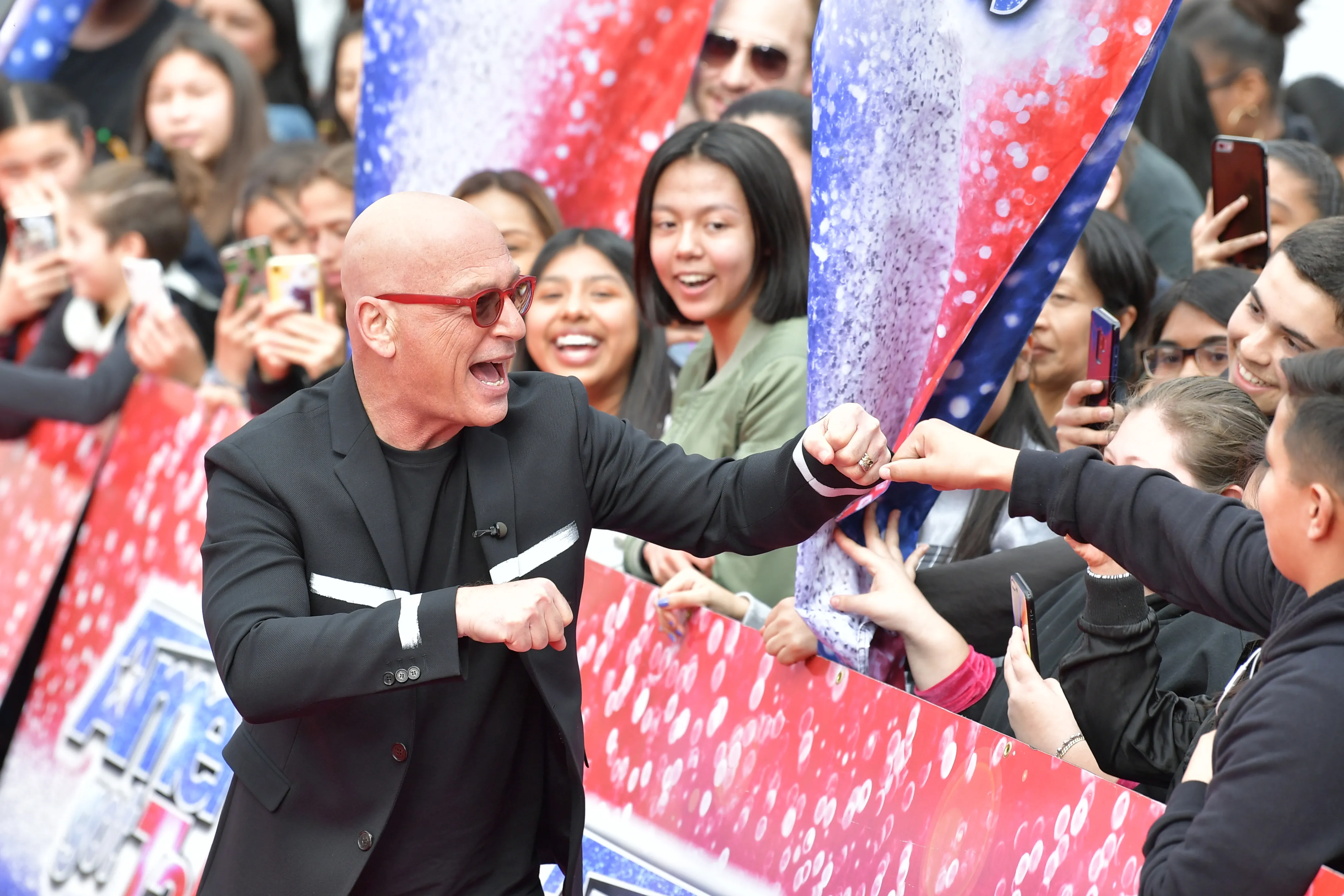 Howie Mandel interacts with fans, giving a fist bump to one person in a crowd.