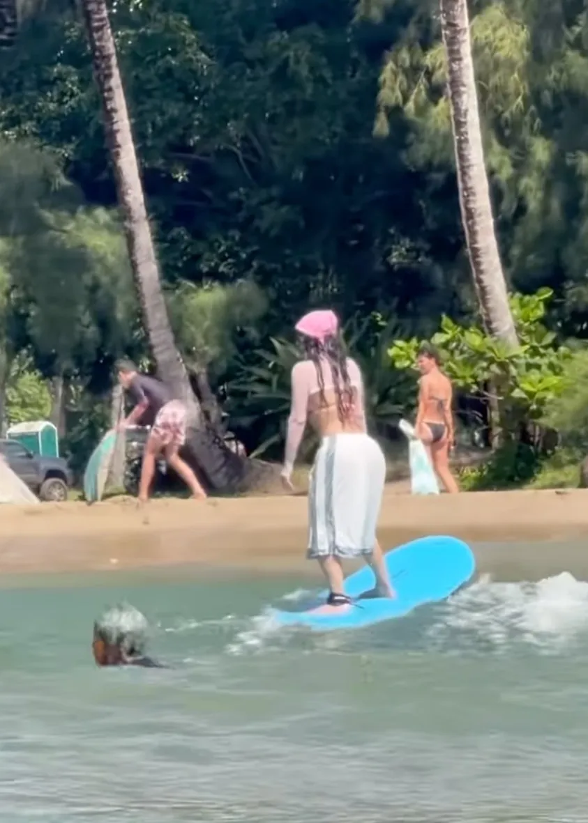 Kim Kardashian surfing on a blue board in the ocean.