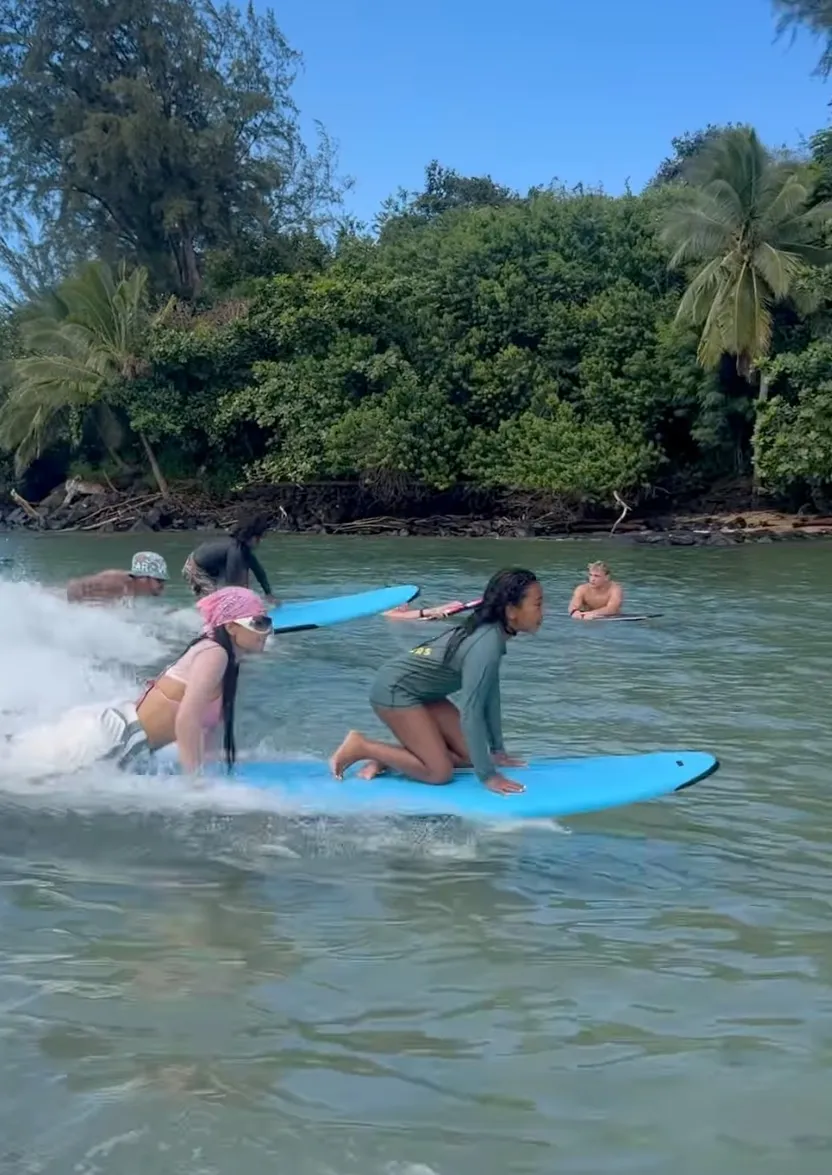 Kim Kardashian surfing with a group of people.