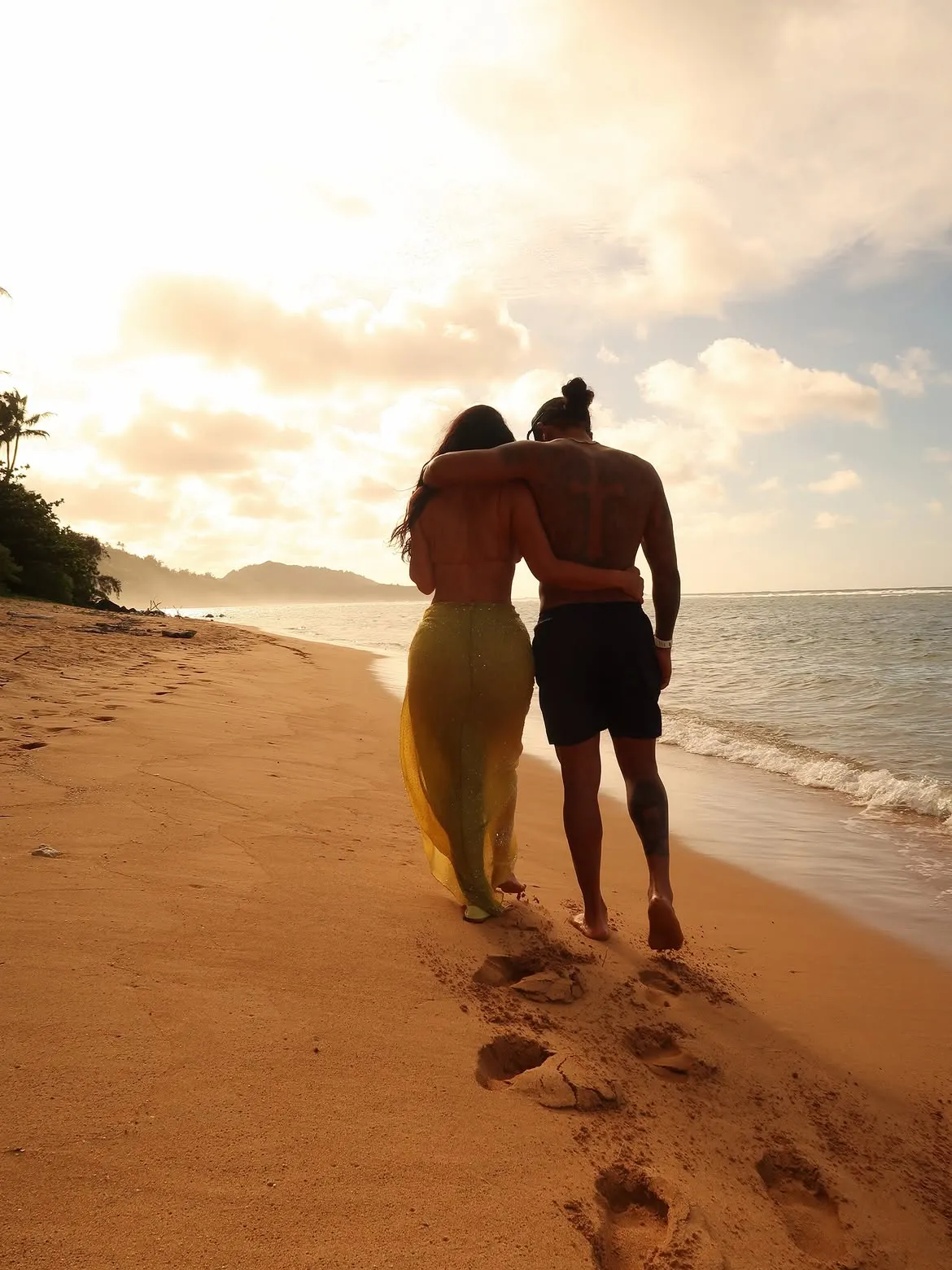 Kim Kardashian and Lewis Hamilton walking together on a beach.