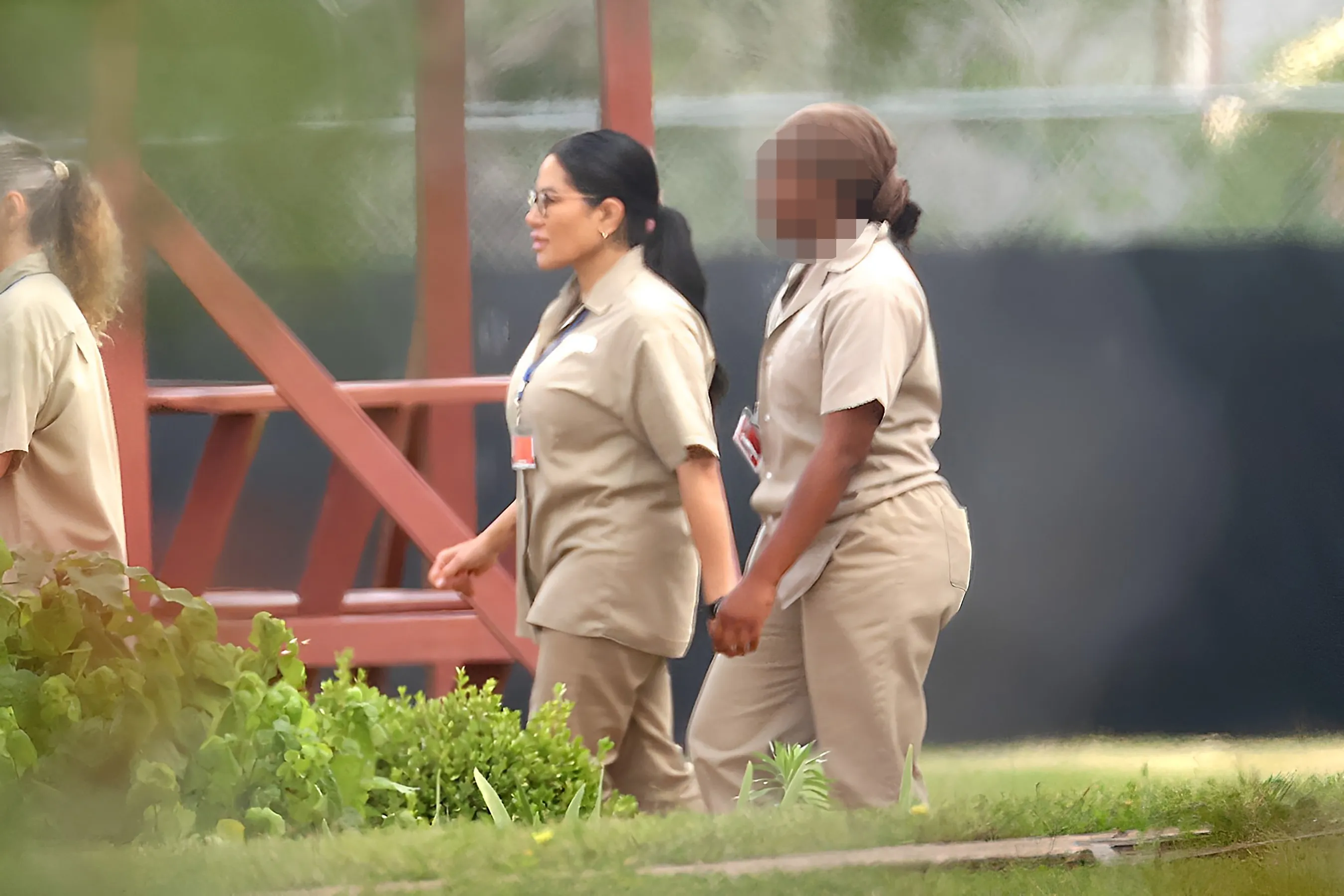 Jen Shah of The Real Housewives of Salt Lake City, wearing a beige prison uniform and glasses, walks with a fellow inmate.