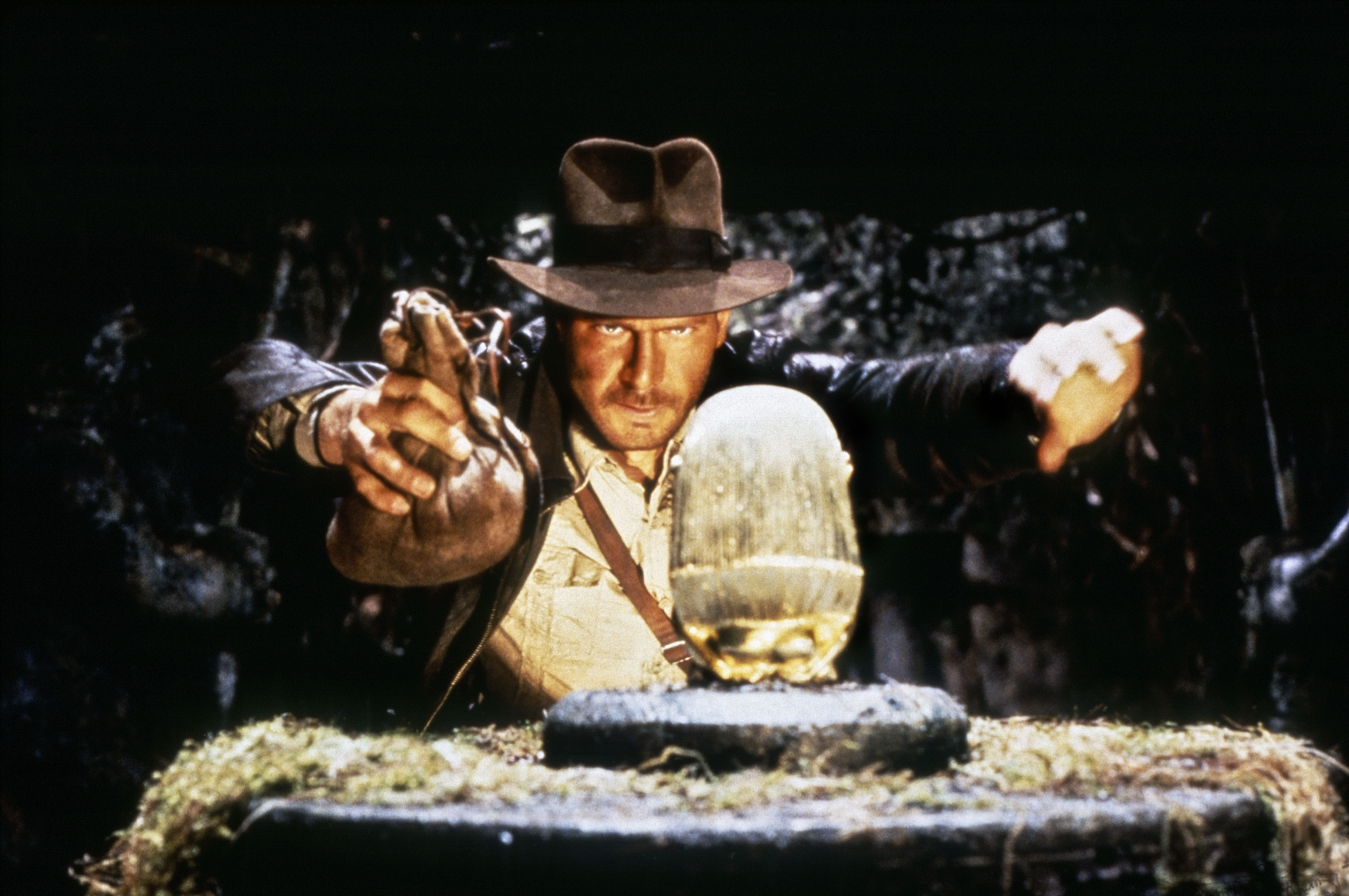Harrison Ford as Indiana Jones, poised to replace an idol with a bag of sand.