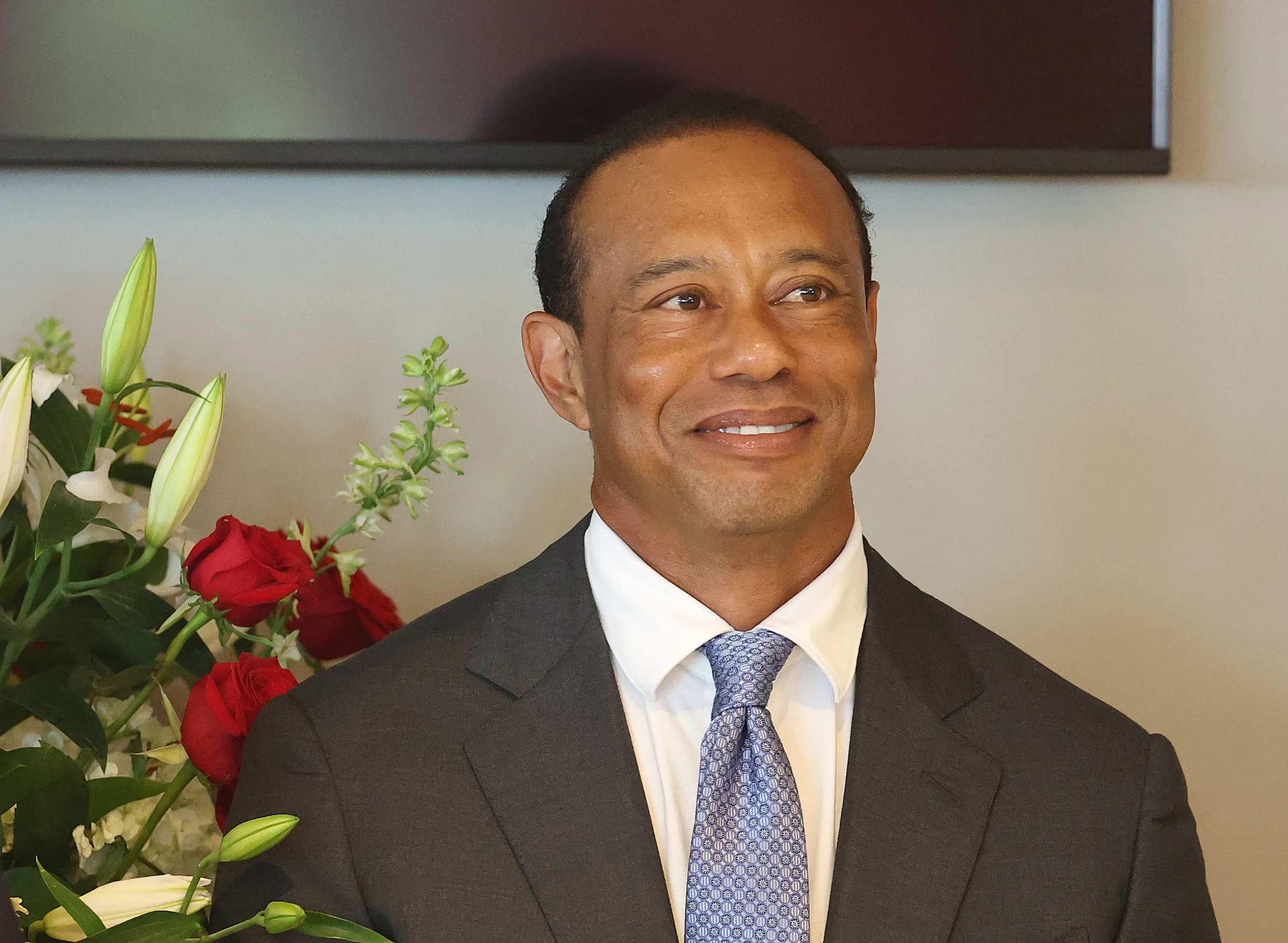 Tiger Woods smiling in a suit during a press conference.