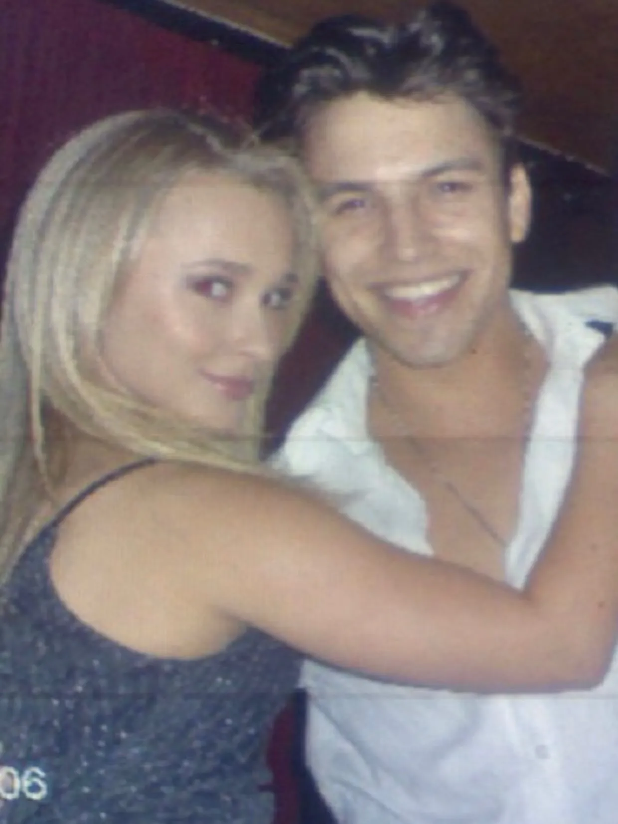 A woman with long blonde hair in a black top and a smiling man in a white shirt with an open collar posing for a photo.