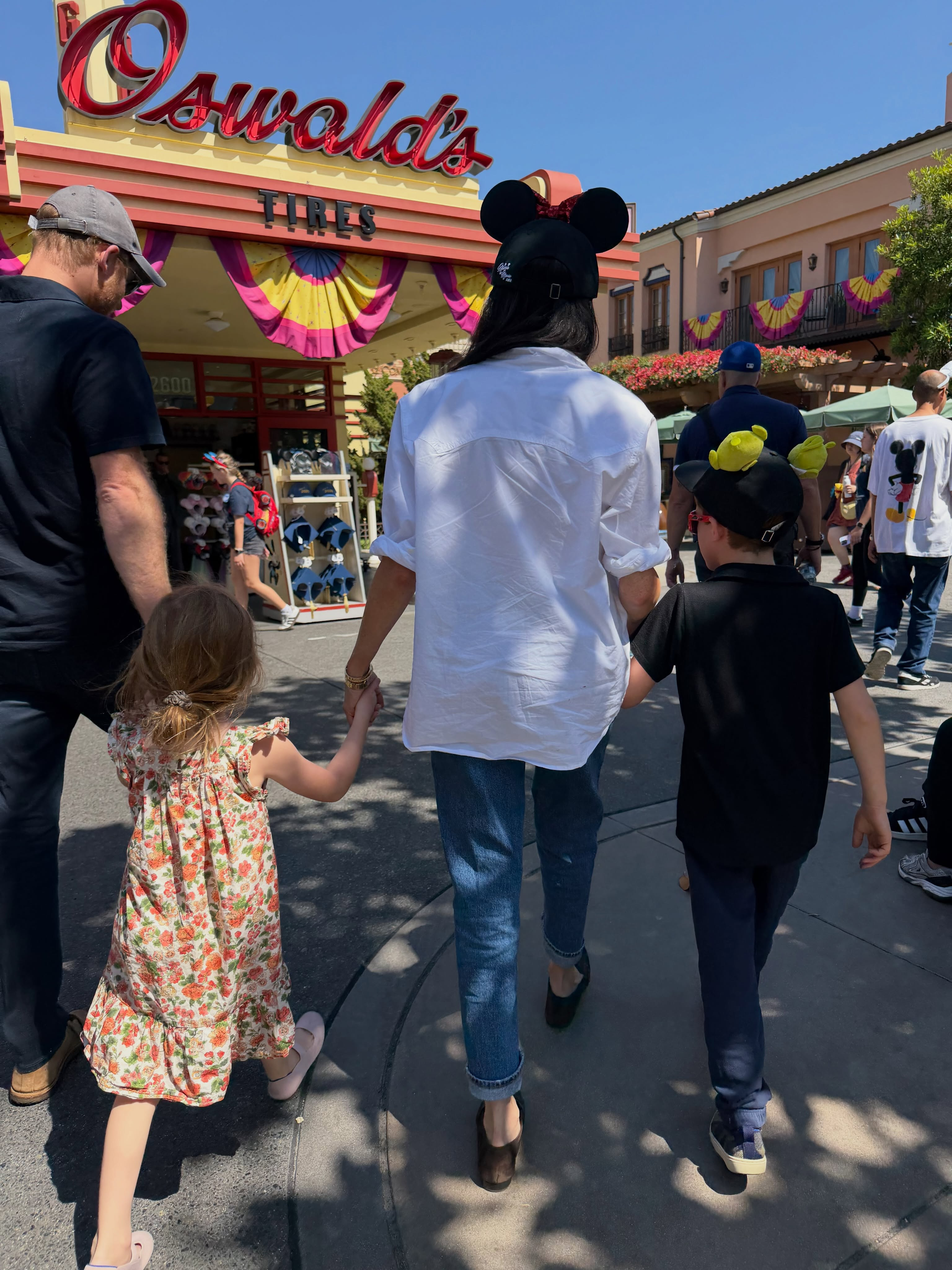 Meghan Markle, in a white shirt, blue jeans and Minnie Mouse ears, Prince Harry, in a black T-shirt, jeans and khaki baseball cap, and their children, Prince Archie, in a black T-shirt and jeans, and Princess Lilibet, i