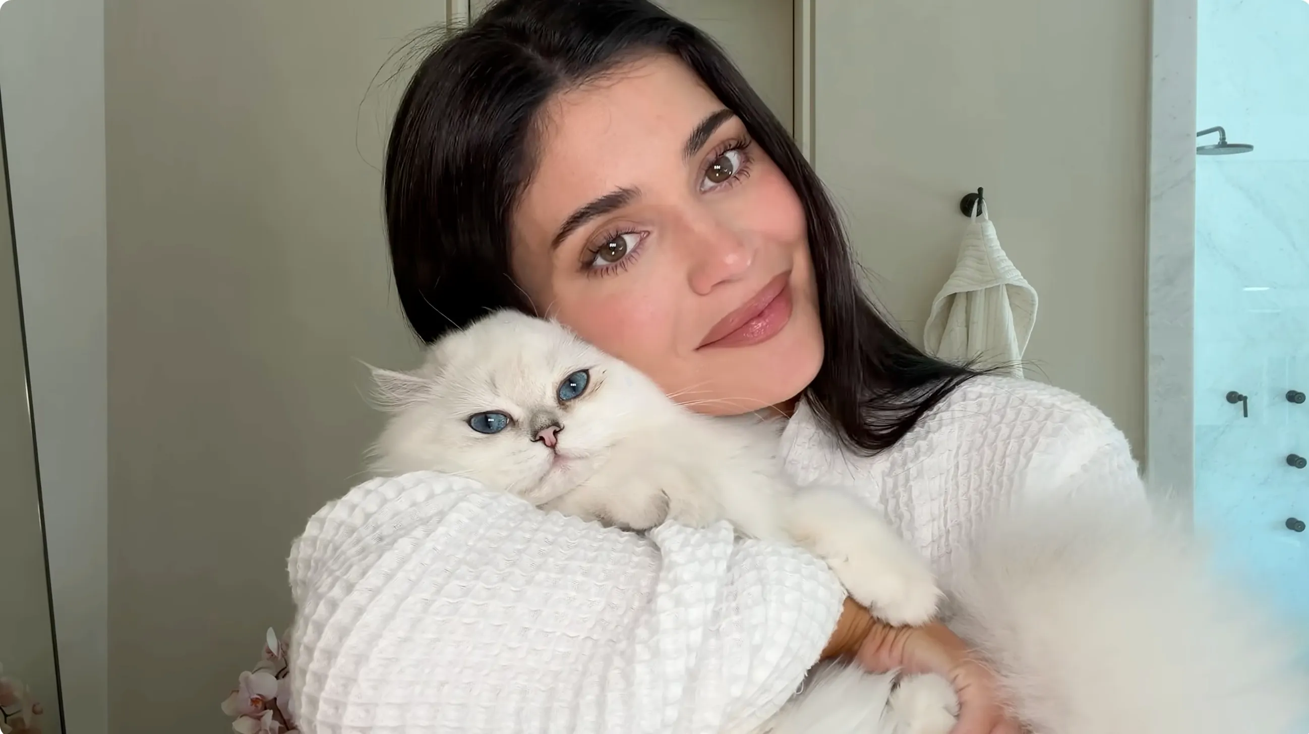 Kylie Jenner holding a white cat with blue eyes.