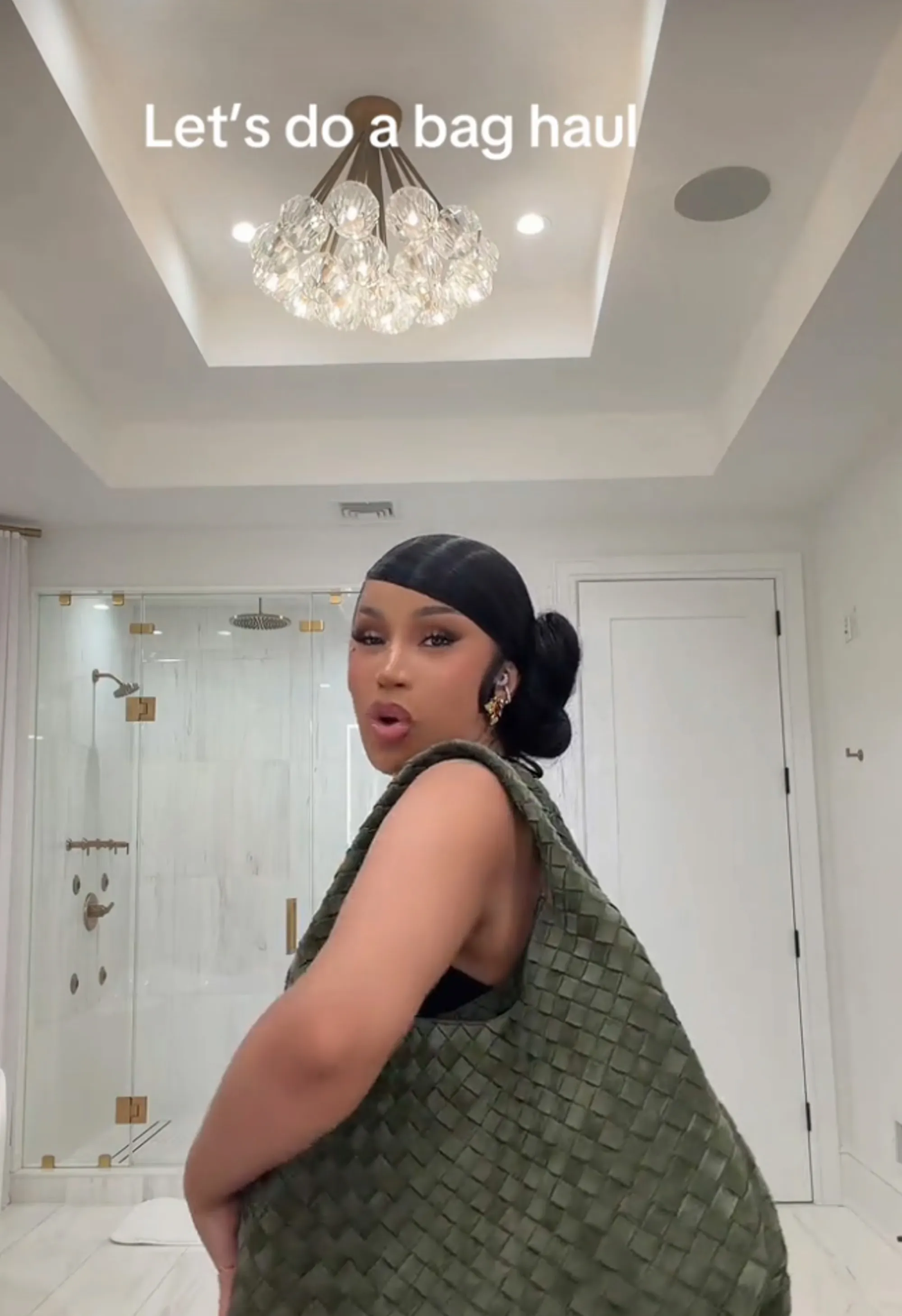 Cardi B showcasing a green woven handbag.