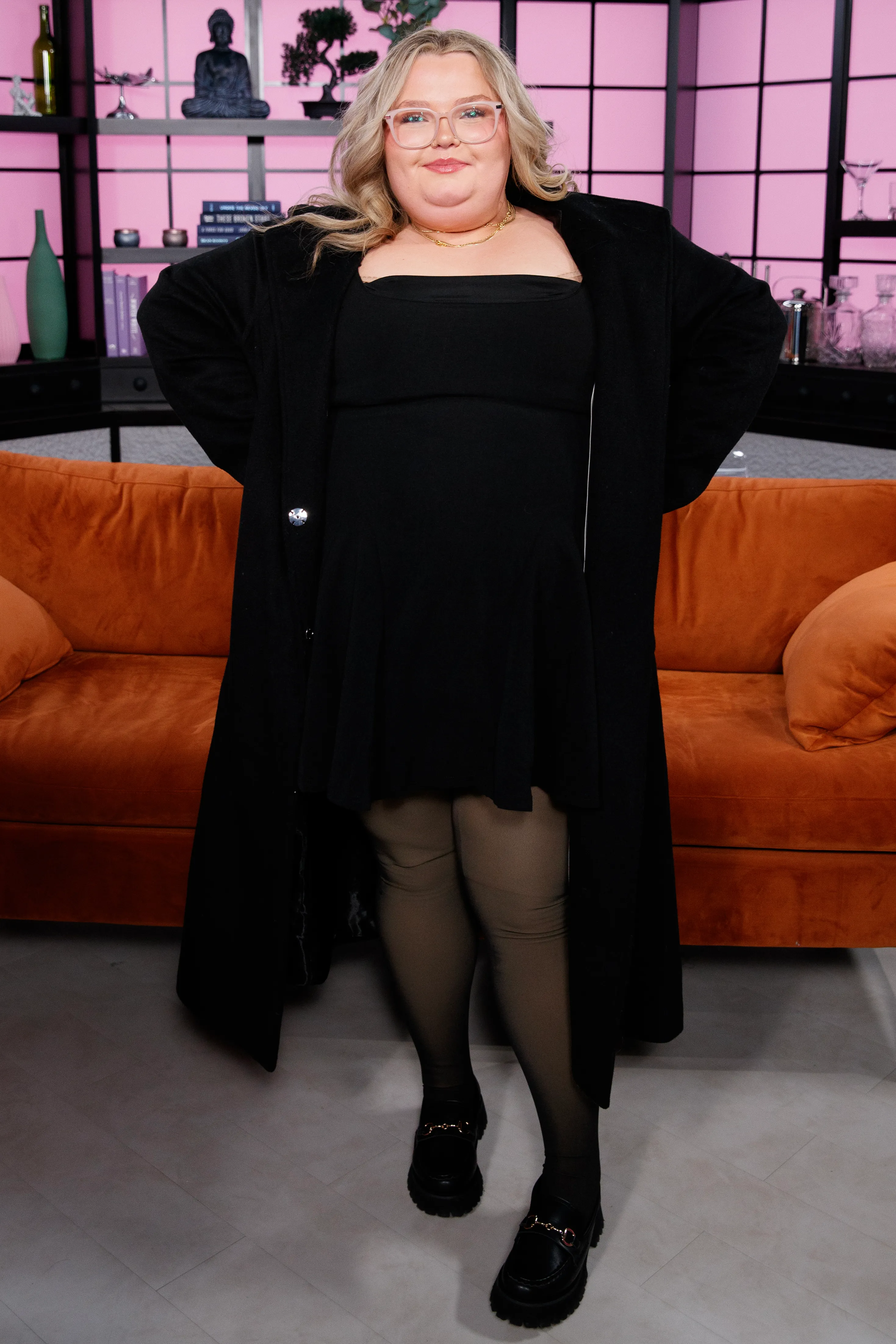 Jessica "Chubbs" Shannon in a black dress and coat, posing for a Virtual Reali-Tea interview.