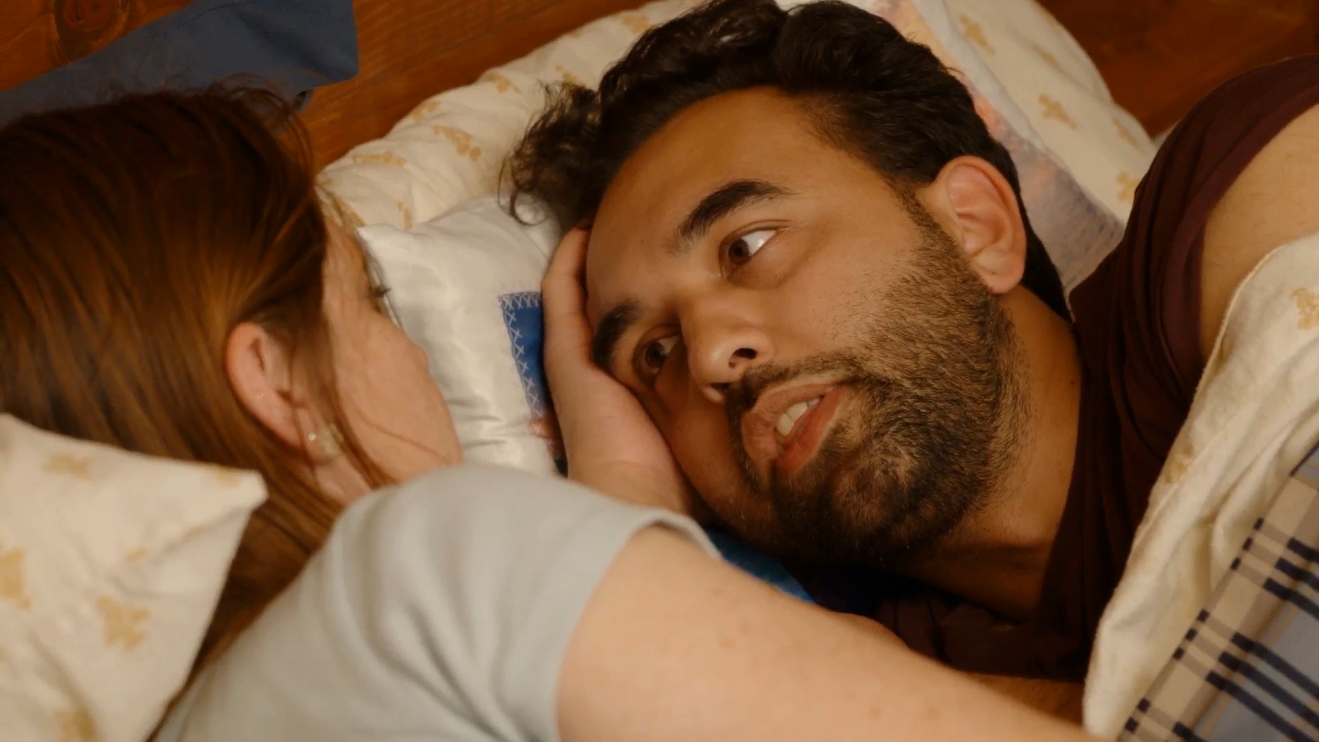 Catie asks Josh a question in bed.
