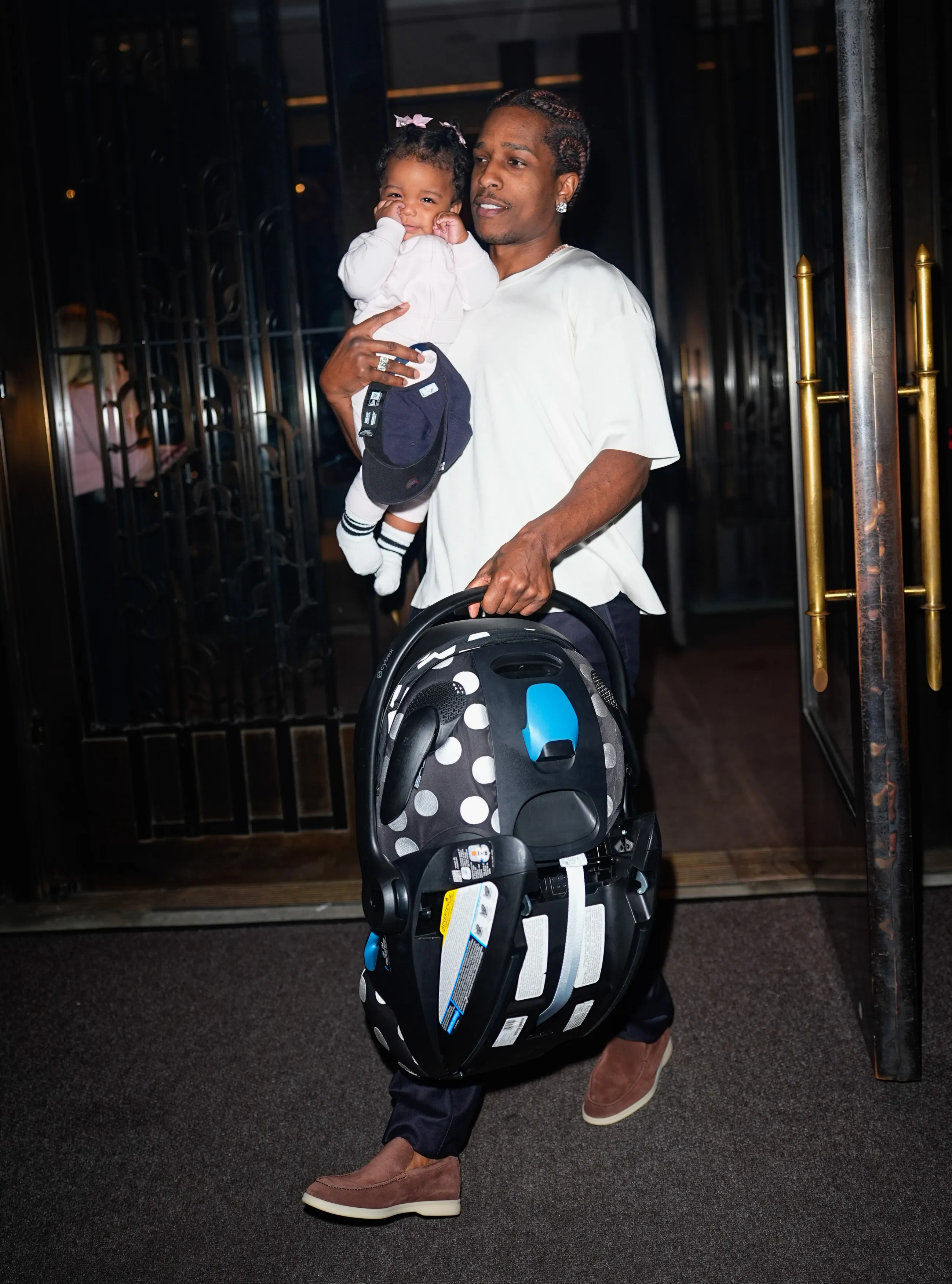 ASAP Rocky carrying a baby and a car seat out of the Four Seasons Hotel.