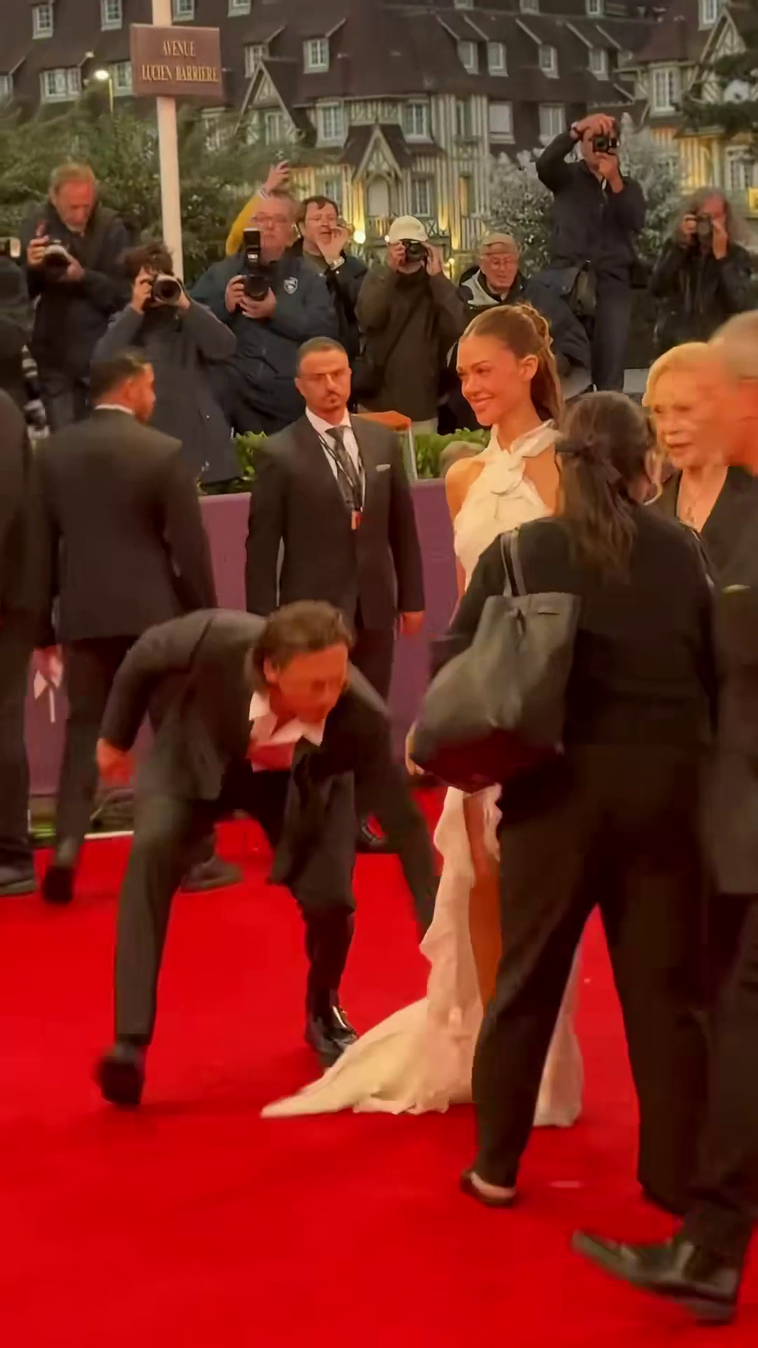Brooklyn Beckham bending down to adjust Nicola Peltz