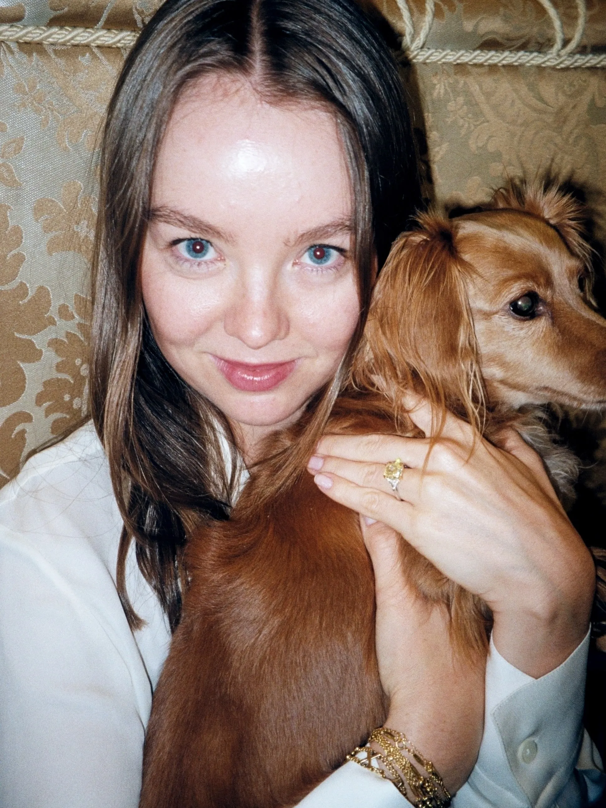 Princess Alexandra of Hanover holds a small brown dog and shows her yellow diamond engagement ring.