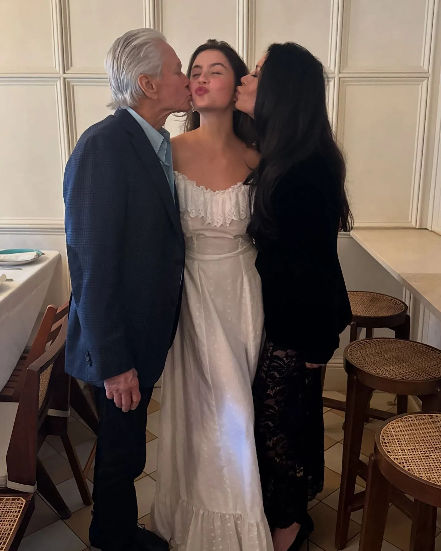 Michael Douglas and Catherine Zeta-Jones kissing their daughter, Carys, on the cheeks.