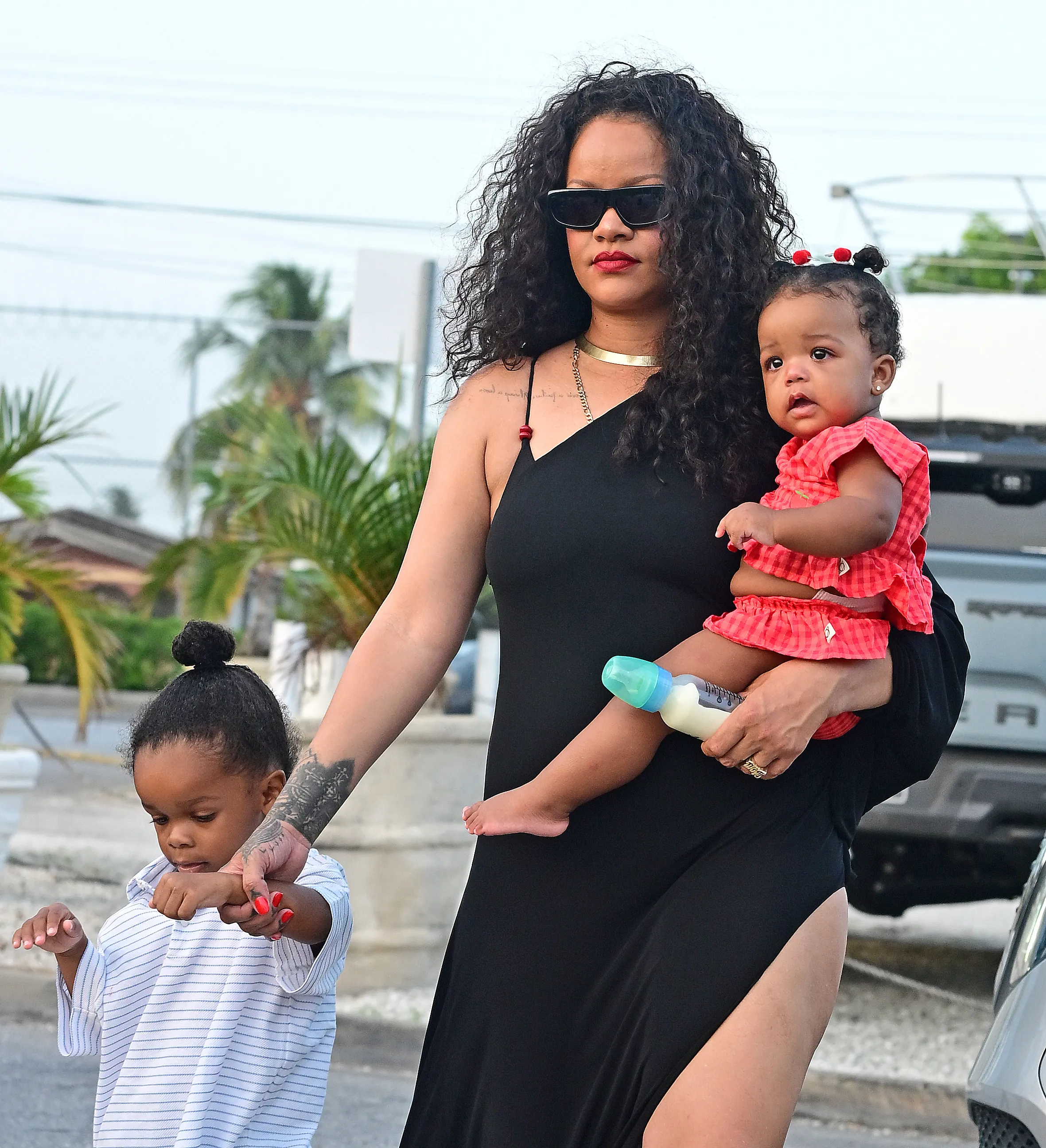 Rihanna holding baby Rocki, and holding hands with RZA, during a family vacation.