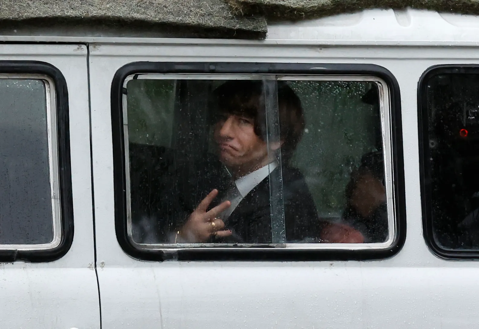 Barry Keoghan as Ringo Starr making a peace sign and a funny face from a bus window.