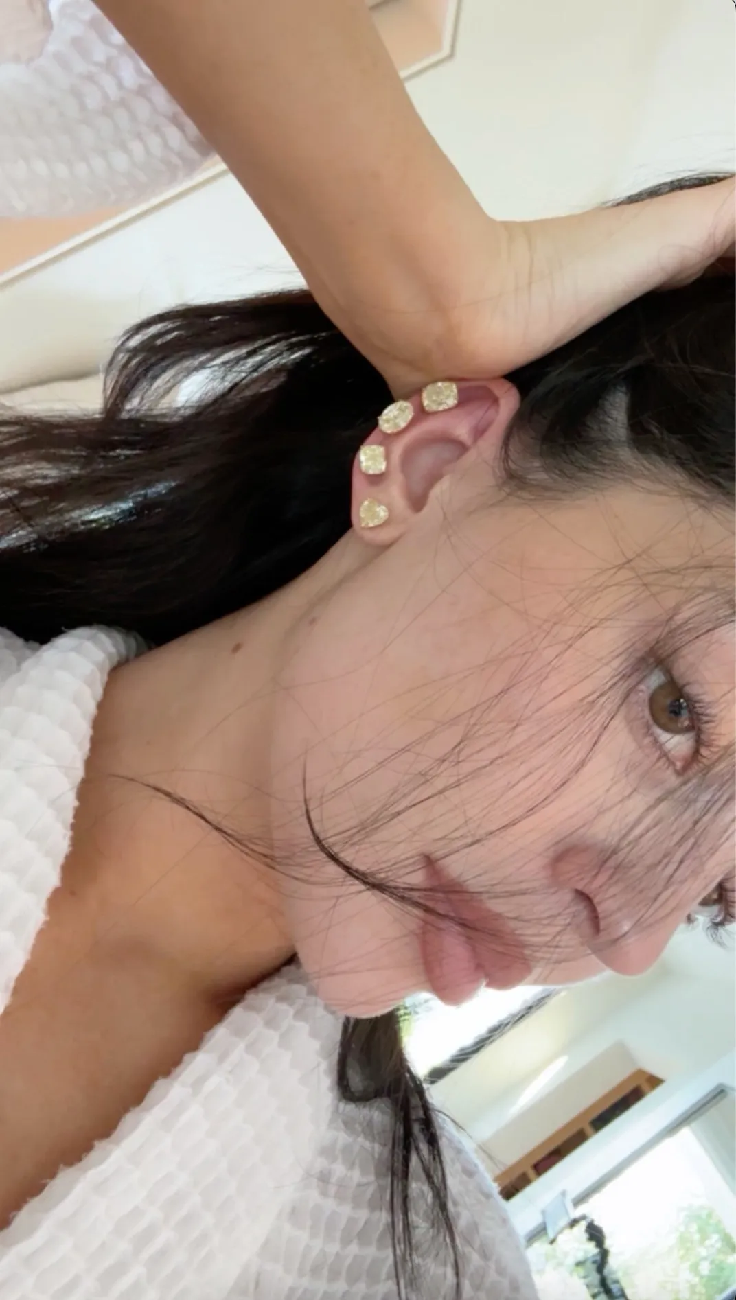 Kylie Jenner wearing multiple diamond earrings in her ear.