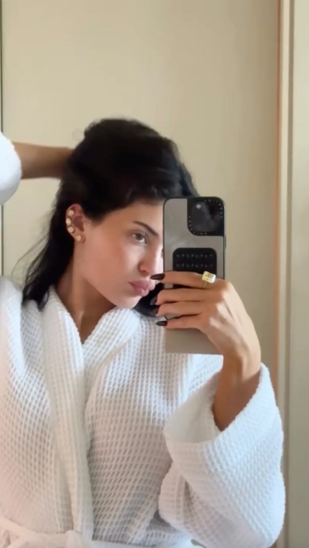 Kylie Jenner wears diamond earrings and a ring while taking a mirror selfie.