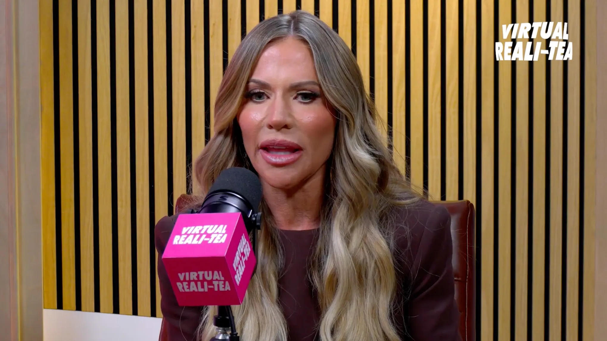 Jenn Pedranti speaking into a microphone with "Virtual Reali-Tea" logos visible.