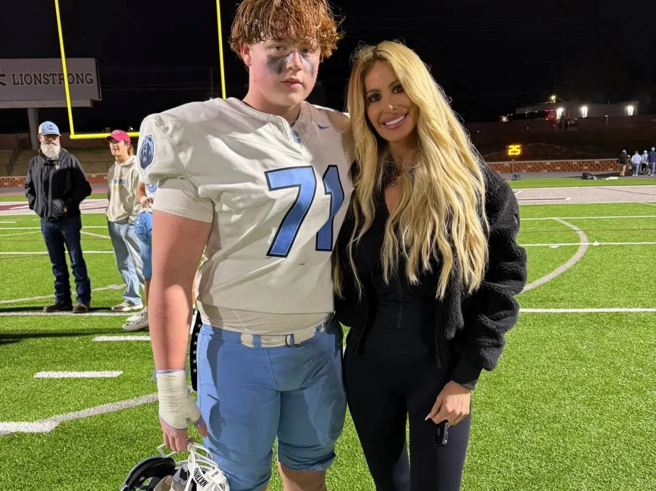 Kim Zolciak and her son Kroy Jagger (KJ) Biermann on a football field.