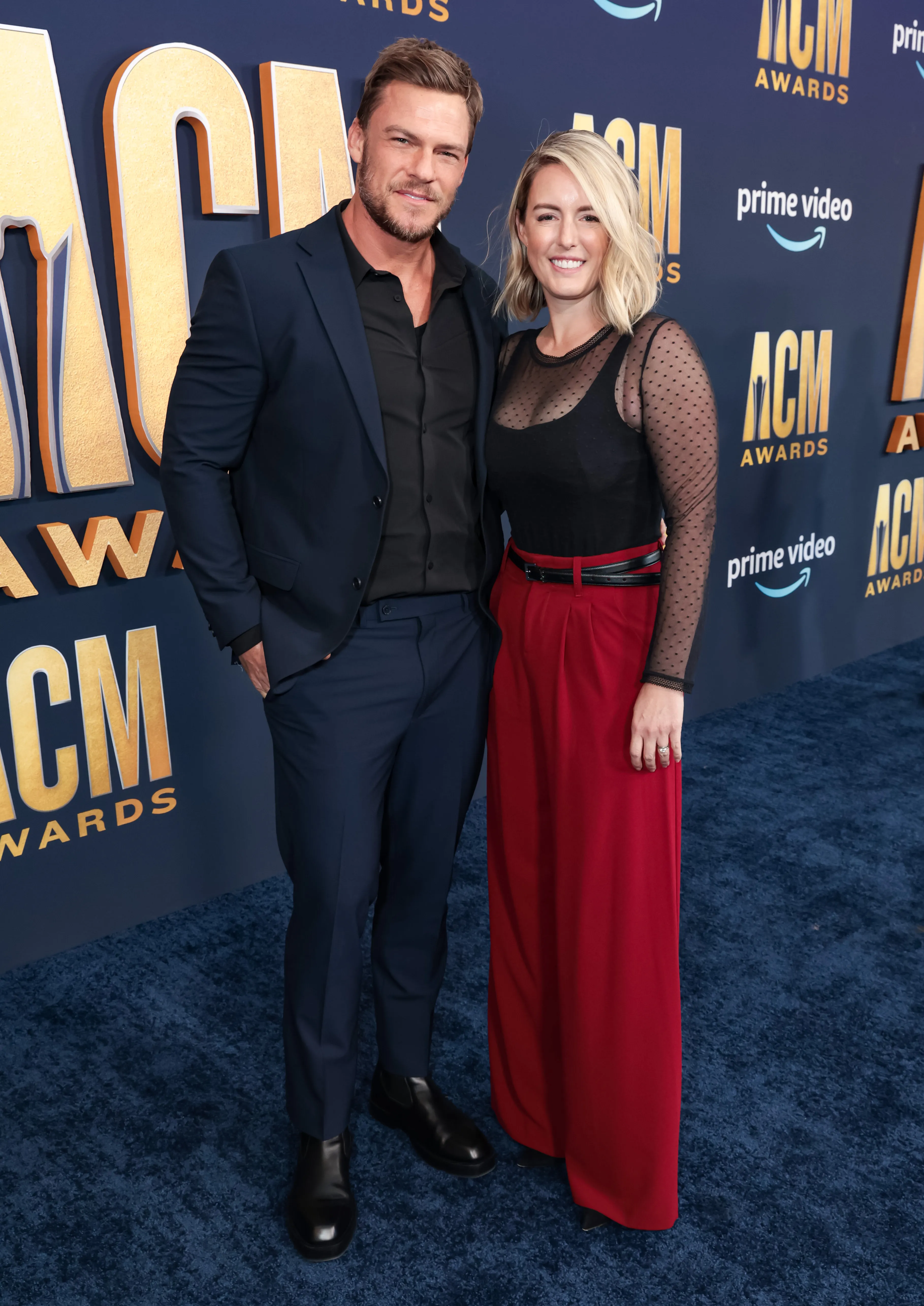 Alan Ritchson and Catherine Ritchson posing on the red carpet at the 57th Academy of Country Music Awards.