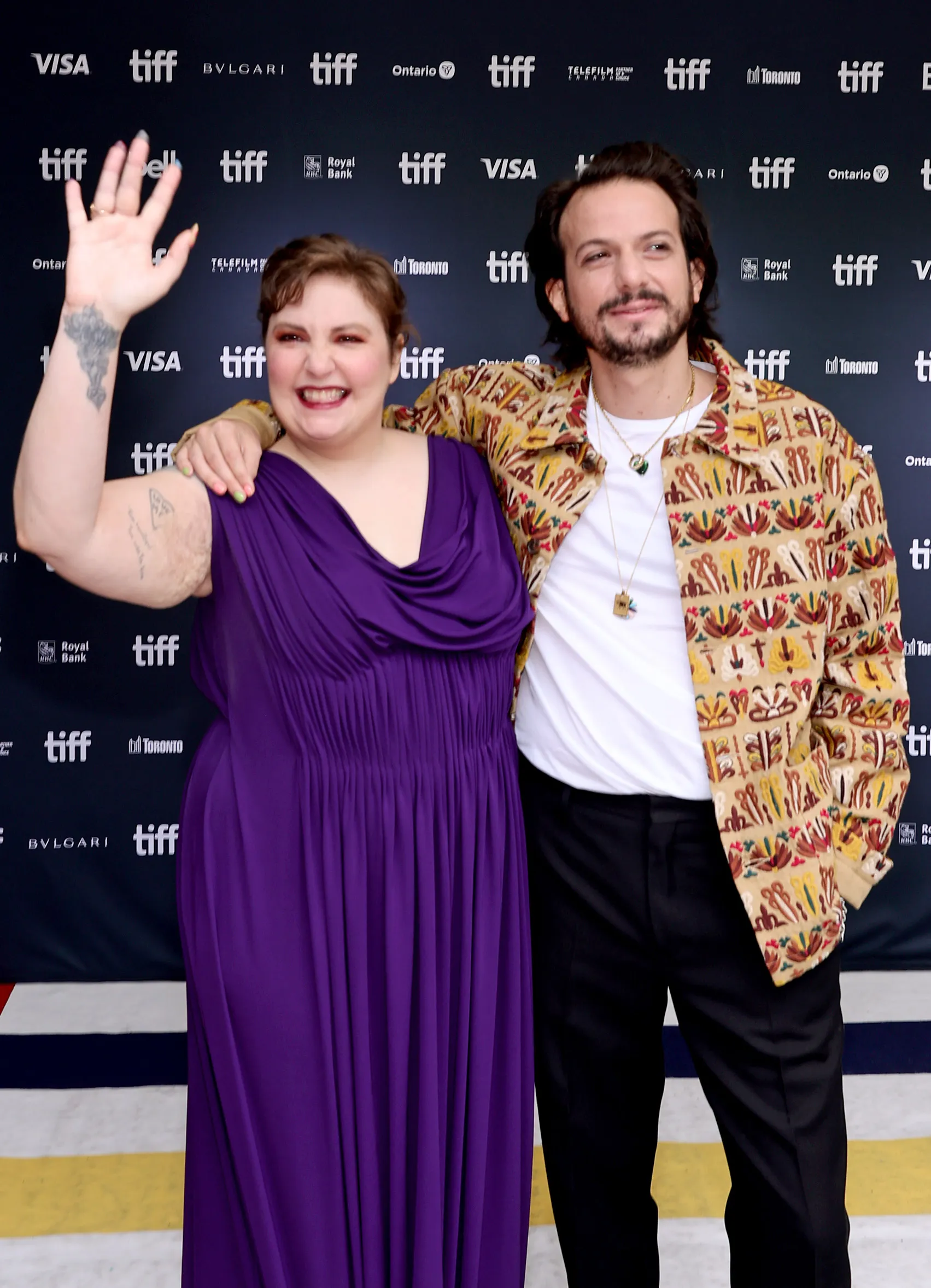 Lena Dunham in a purple dress and Luis Felber in a patterned jacket attend the "Catherine Called Birdy" premiere.