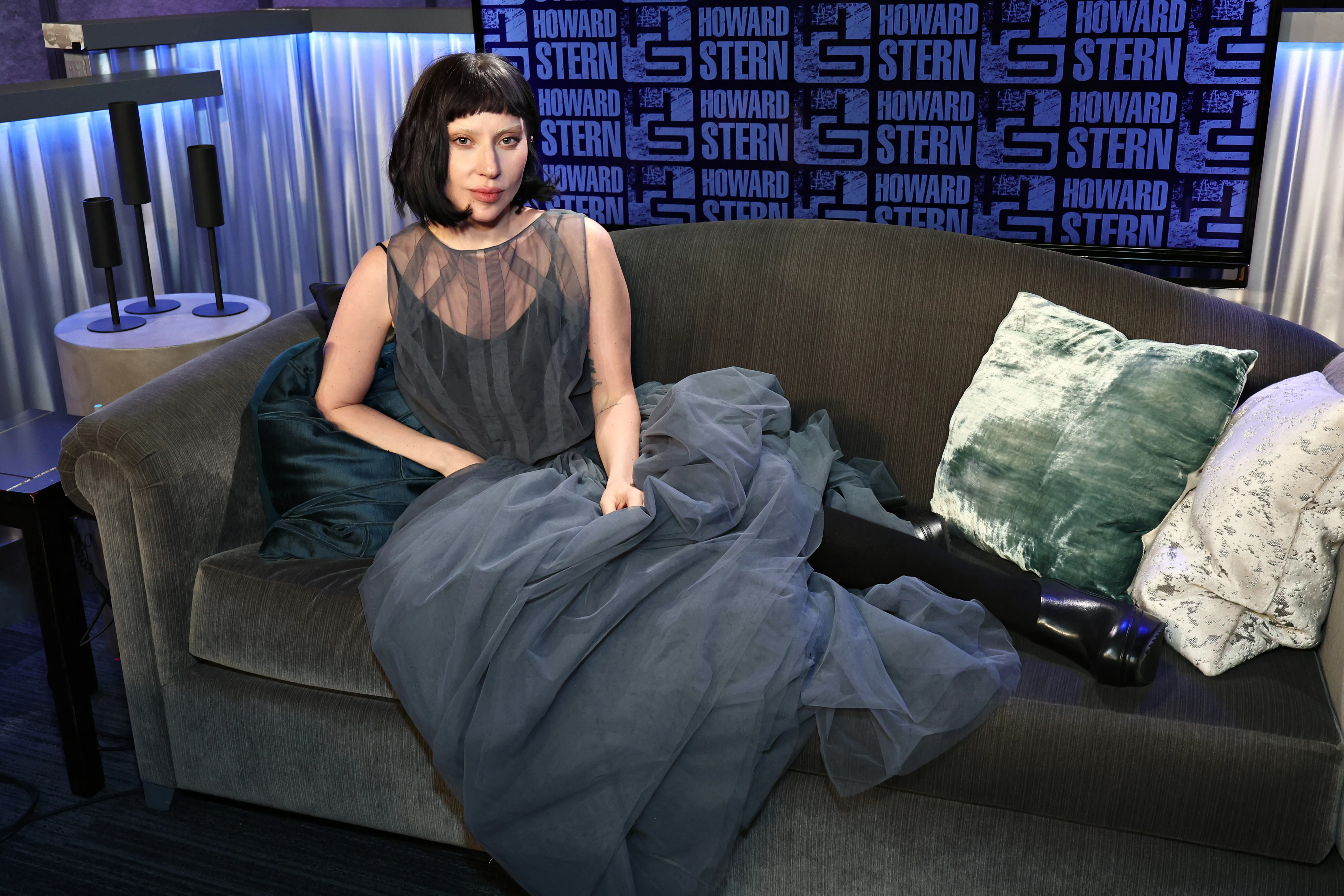 Lady Gaga sitting on a couch in a sheer gray gown at SiriusXM