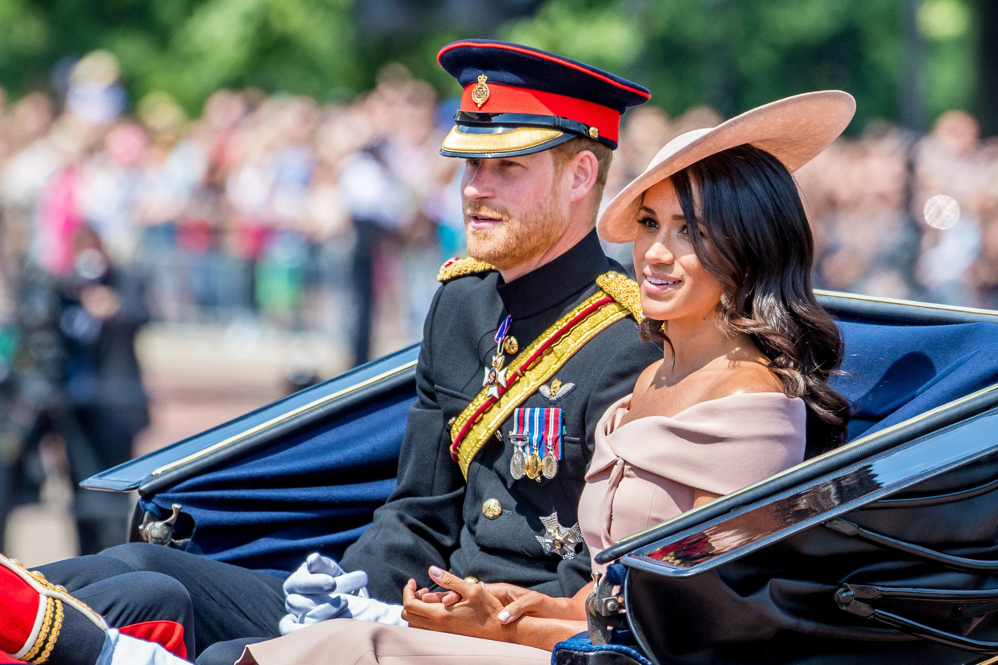 Prince Harry in military uniform and Meghan Markle in formal wear ride in a carriage.