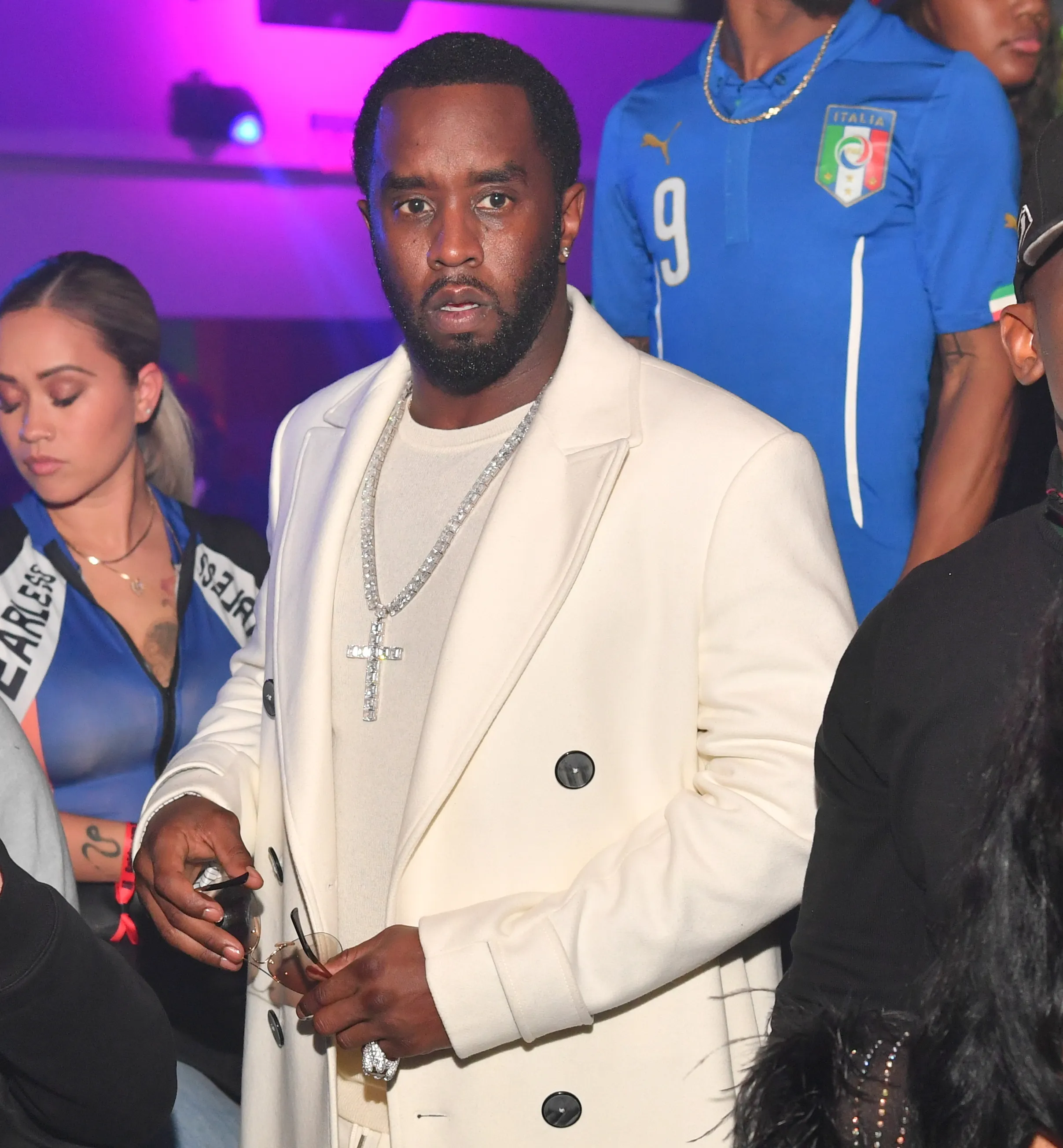 Sean "Diddy" Combs wears a white jacket and a diamond cross necklace.
