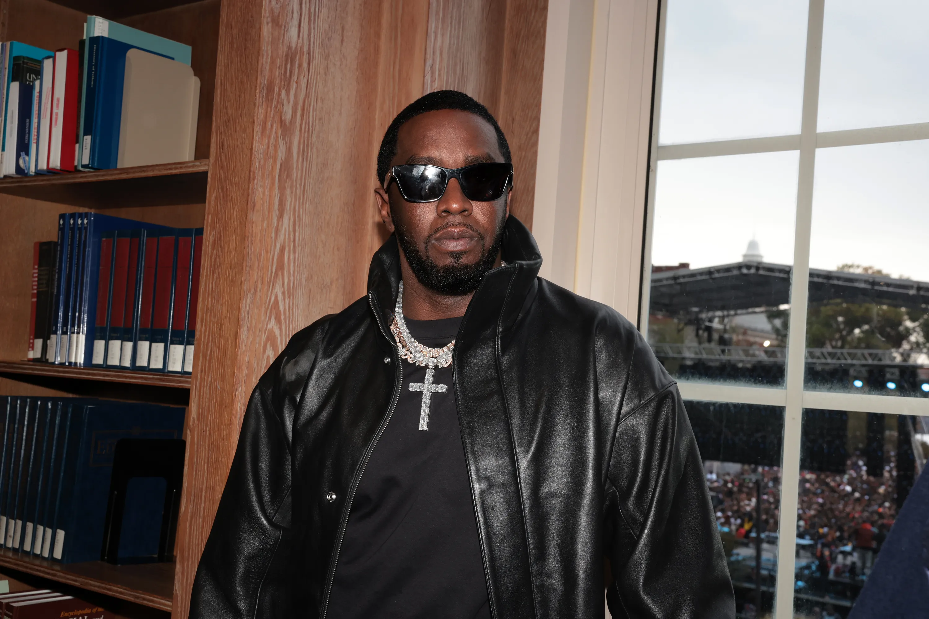 Sean "Diddy" Combs stands in a black leather jacket and sunglasses.
