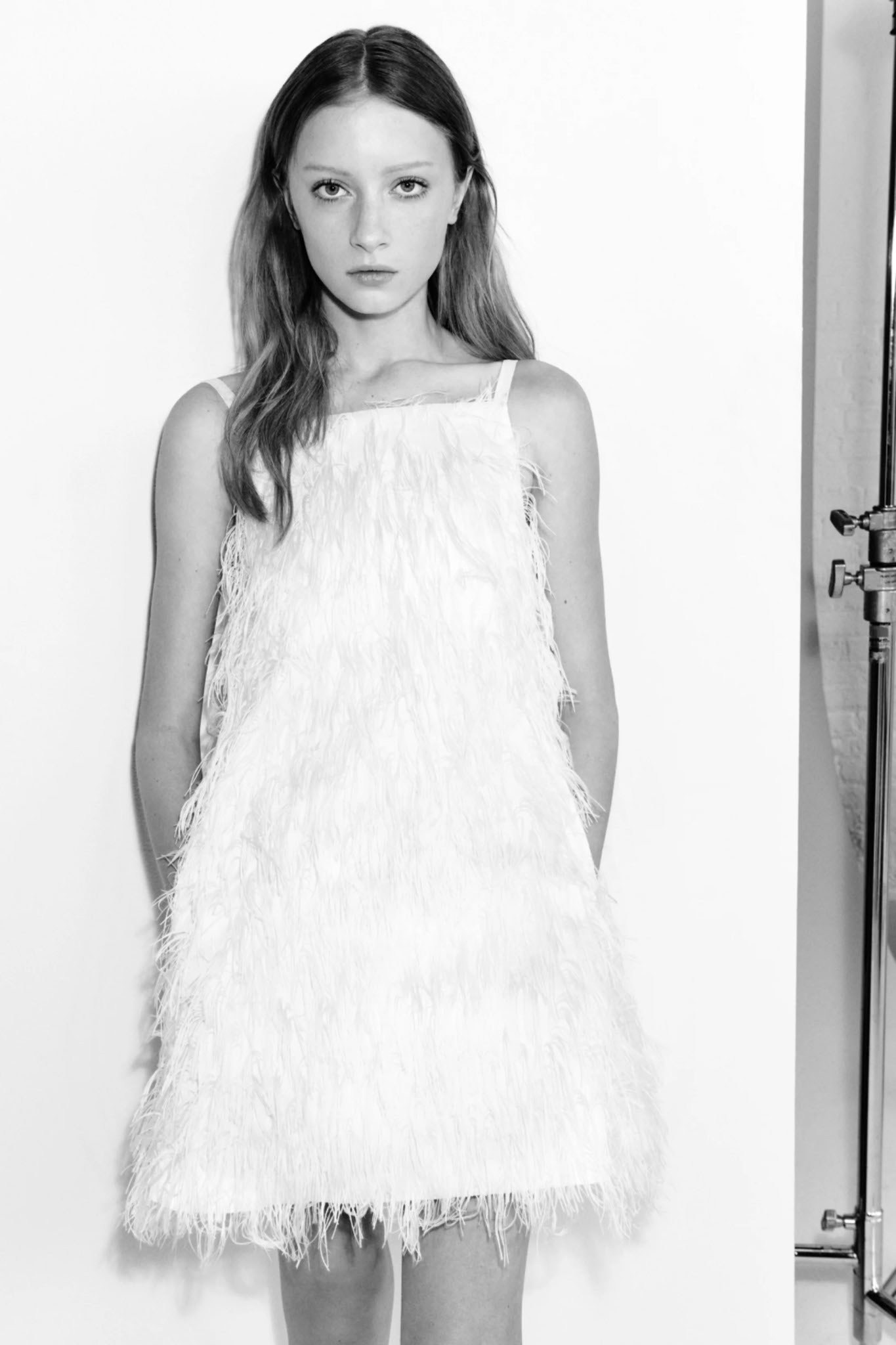 A model wearing a white feathered mini-dress from the Simkhai Fall 2026 collection.