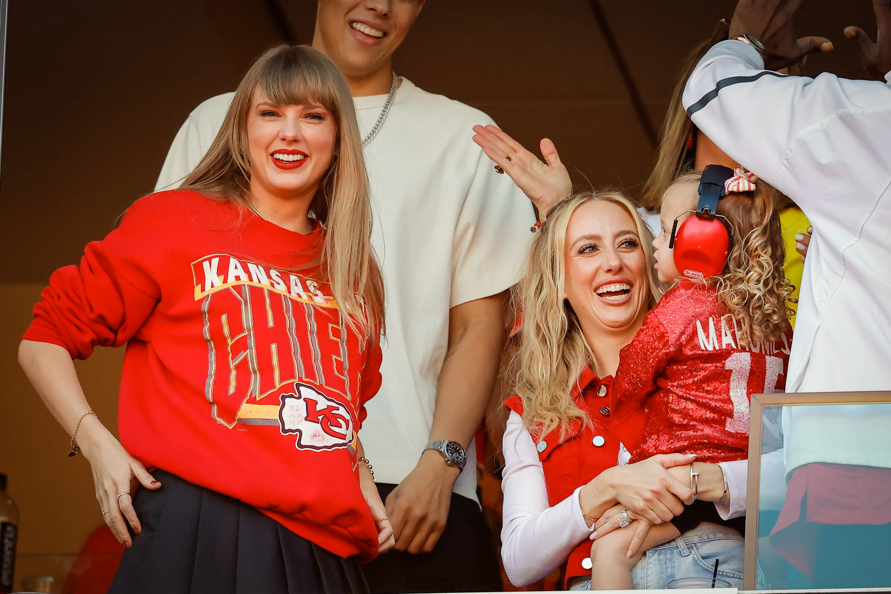 Taylor Swift and Brittany Mahomes smiling at a Kansas City Chiefs game.